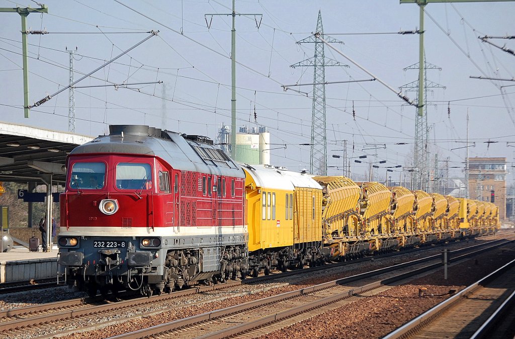 Die DB Bahnbau Gruppe mit 232 223-8 (Lugansk Bj.1975) mit Gleisbauzug mit Bahndienstwagen und einer Reihe Materialfrder- und Siloeinheiten MFS 100 bei der Durchfahrt im Bhf. Flughafen Berlin-Schnefeld, 22.02.11 