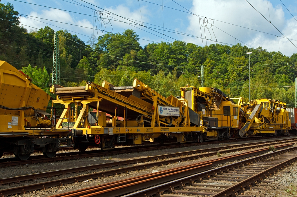 Abgestellt in Betzdorf/Sieg am 22.09.2012:
Plasser & Theurer Zwei-Wege-Bettungsreinigungsmaschine ZRM 79 (Schweres Nebenfahrzeug Nr. 97 11 52 502 17-7) der MGW Gleis- und Weichenbau-GmbH (Berlin). 
Die Maschine wurde 1981 unter der Fabriknummer 193 gebaut. 
Sie hat ein Gewicht von 95 t, 6 Achsen, die L�nge �ber Puffer betr�gt 28.060 mm, die zugelassene Streckenklasse ist C 2, die H�chstgeschwindigkeit bei Eigenfahrt betr�gt 80 km/h – im Zugverband 90 km/h. Durch ein Raupenfahrwerk ist sie gleislos fahrbar.
Recht davor eine Plasser & Theurer gleisfahrbare Beladestation BLS 2000 gf (Schweres Nebenfahrzeug Nr. 97 19 269 0 357-8) der MGW. 
Sie wurde 2003 unter der Fabriknummer 4063 gebaut, das Gewicht betr�gt 22 t, auf 2 Achsen, , die L�nge �ber Puffer betr�gt 12.780 mm, die H�chstgeschwindigkeit im Zugverband 100 km/h.
Davor sind noch einige Plasser & Theurer Materialf�rder- und Siloeinheiten MFS 100.