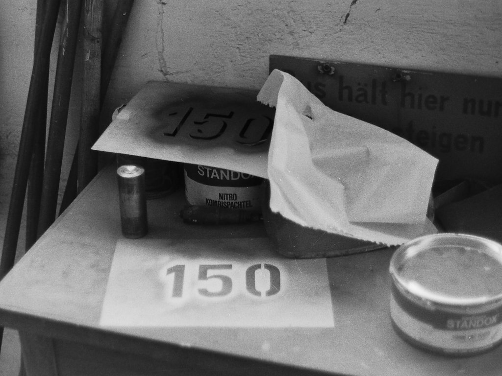 An dieser Stelle sollte mal ein Blick hinter die Kulissen erlaubt sein. Die Oldenburger Vorortbahnen Pekol besa�en in ihrem Depot in der Alexanderstra�e nicht nur Werkst�tten die Reparaturen aller Art erlaubten, sondern auch mehrere Lackierboxen in denen, z.T, mit Unterst�tzung professioneller Lackierer und Grafikern, komplette Beschriftungen sowie gr��ere oder auch kleinere Reparaturen durchgef�hrt wurden. Auf diesem Bild, dass am 22.02.82 entstand, sind die beiden Schablonen zu sehen, mit denen z.B. die Nummernbeschriftung an Wagen 150 durchgef�hrt wurde. Zun�chst wurde mit der unteren Schablone mit wei�er Farbe die Ziffer angebracht, und dann mit der oberen in dunklem Gr�n, der Schatten hinzugef�gt. Fertig !  