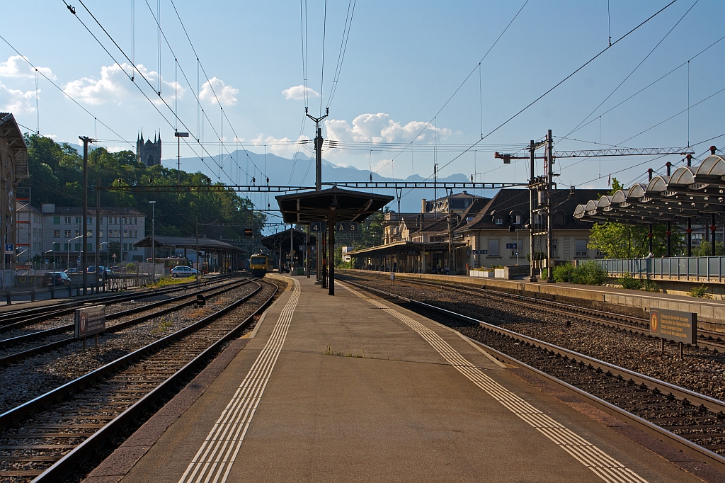 Blick (von Westen) auf den Bahnhof Vevey an der Waadtl�nder Riviera (Genfersee), am 28.05.2012. 

Der Bahnhof ist ein Knotenpunkt des �ffentlichen Verkehrs, an die Genferseestrecke der SBB, schliessen hier die Strecken der VCh und der MVR an.
Er wurde 1861 im Zuge der Streckener�ffnung Lausanne–Villeneuve der heutigen Simplonbahn er�ffnet.

1902 wurde der Betrieb auf der heutigen MVR-Schmalspurlinie nach Blonay aufgenommen; 1904 die ebenfalls schmalspurige Strecke nach Ch�tel-Saint-Denis dem Verkehr �bergeben. Im selben Jahr wurde die VCh-Strecke zum Bahnhof Puidoux-Chexbres an der Bahnstrecke Lausanne–Bern er�ffnet. Die Schmalspurlinie nach Ch�tel-Saint-Denis wurde 1969 stillgelegt und durch eine Buslinie ersetzt.

�hnlich wie beim Bahnhof Montreux liegt der �bergang zum Hausbahnsteig nicht im Erdgeschoss des Bahnhofsgeb�udes, sondern im ersten Obergeschoss. Die Gleisanlage umfasst nebst einigen G�tergeleisen einen Seiten- und zwei Mittelperrons.

Die Geleise 1 und 3 sind dem SBB-Verkehr (der Simplonbahn) vorbehalten (Gleis 2 fehlt), von Gleis 5 - welches mit dem Gleis 3 und dem kurzen Gleis 4 am Mittelbahnsteig liegt, verkehrt der Train des Vignes als S31 nach Puidoux-Chexbres. Der Mittelbahnsteig mit den Gleisen 6 (Normalspur) und 7 (Meterspur), welches im Westteil eine kleine Kurve bildet, dient in der Regel nur dem Verkehr der MVR nach Blonay und Les Pl�iades.