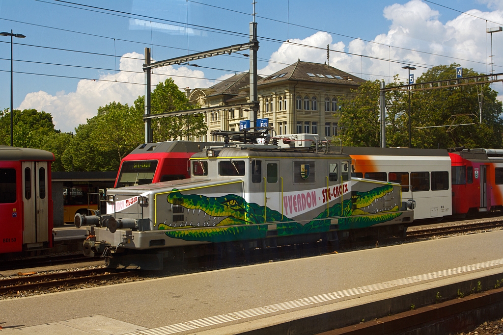 
Das 1.000mm Travys-Krokodil Ge 4/4 - 21  Yverdon & Ste. Croix   der YSteC (Yverdon - Sainte-Croix) steht am 29.05.2012 abgestellt in Yverdon-les-Bains, Bild aufgenommen aus fahrendem ICN. Der Einzelg�nger wurde 1950 gebaut. Mit den Normalspurpuffern kann die Lok dem Verschub von Normalspur G�terwagen vornehmen.  Bei einem Neuanstrich hat die Lok einen zum �bernahmen passende Lackierung erhalten.
Technische Daten: Spurweite  1000 mm;     Fahrleitungsspannung  15000 V, 16.7 Hz ~  ; H�chstgeschwindigkeit  50 km/h ; Achsfolge  Bo' Bo' ; Gewicht  39.0 t;  L�nge �ber Puffer  12.87 m  