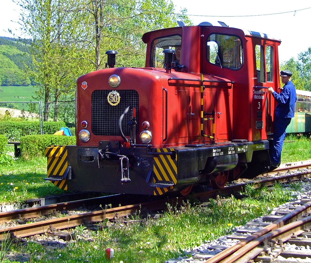 Die O+K Lok V3  NAHMER  der Sauerl�nder Kleinbahn (MME  M�rkische Museums-Eisenbahn), ex V3 der Hohenlimburger Kleinbahn AG (HKB) am 23.05.2010 im Bahnhof H�inghausen beim Umsetzen.

Die Firma Orenstein und Koppel (O&K), Werk Dortmund-Dorstfeld lieferte 1960 insgesamt 5 baugleiche, zweiachsige dieselhydraulische Lokomotiven (1.000 mm Spurweite) des Typs MV8 mit Endf�hrerstand, an die Hohenlimburger Kleinbahn AG. 
Die Lokomotiven waren mit einer pneumatischen Mehrfachsteuerung ausger�stet, da die Z�ge ins Nahmertal gr��tenteils mit 2 Maschinen gefahren werden mussten. Die Kraft�bertragung auf die R�der erfolgt �ber Blindwelle und Kuppelstangen. Bis zur Betriebseinstellung der HKB am 23.12.1983 waren die Maschinenim Einsatz.
Am 28.07.1984 gelangte die Lok Nr.3 in den Besitz der M�rkischen Museumseisenbahn (MME). Dort erhielt sie in Erinnerung an ihre alte Heimat den Namen  NAHMER , nach dem gleichnamigen Bach in dessen Tal die Bahn verlief.

Technische Daten:
Fabriknummer: 25988
Spurweite: 1.000 mm
L�nge �ber Puffer: 5.900 mm
Achsabstand: 1.500 mm
Dienstgewicht: 20.700 kg
Motor: Orenstein & Koppel wassergek�hlter 6 Zylinder 4-takt Dieselmotor 116 V6 D 
Hubraum: 10,85l
Motorleistung: 140 PS (103 kW) bei 1.500 U/min
Getriebe: Voith L22 nV Zweigang-Turbogetriebe (Wandler+Kupplung)
H�chstgeschwindigkeit: 17,5 km/h