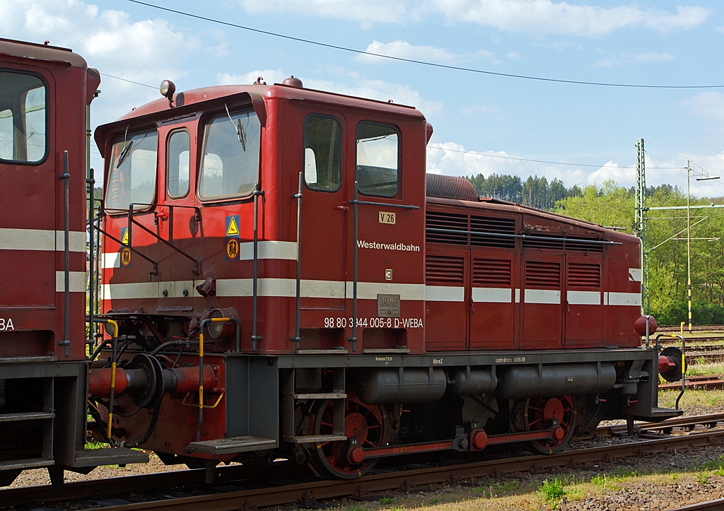 Die Westerwaldbahn (WEBA) Lok 3 (V 26.3) am 06.05.2013 in Scheuerfeld/Sieg. 

Die Jung Lok vom Typ R 30 B wurden bei der Firma Jung in Kirchen/Sieg 1957 unter der Fabriknummer 12748 gebaut und als V 26.3 an die WEBA geliefert. 
Hier in Doppeltraktion abgestellt (links die V 26.1), in dieser Einsatzform werden sie F�hrerhaus an F�hrerhaus gekuppelt, an den F�hrerhausr�ckw�nden sind �bergangsm�glichkeiten zur jeweils anderen Maschine.
Die WEBA hatte 4 dieser Jung R 30 B Loks, diese zwei Loks sind heute noch als Reserveloks erhalten geblieben. 
Sie hat die NVR-Nummer 98 80 3944 005-8 D-WEBA.
Die Maschinen besitzen ein hydraulisches Getriebe (diesel-hydraulische Lok),  die Kraft�bertragung erfolgt vom Getriebe mittels Blindwellen �ber Treibstangen auf die R�der. 

Technische Daten: 
Achsformel: B
L�nge �ber Puffer:  7.680 mm
Achsabstand: 3.000 mm
Gewicht der Lok: 28 t
H�chstgeschwindigkeit: 46 km/h (23,4 km/h im Rangiergang)
Leistung: 191 kW (260 PS)