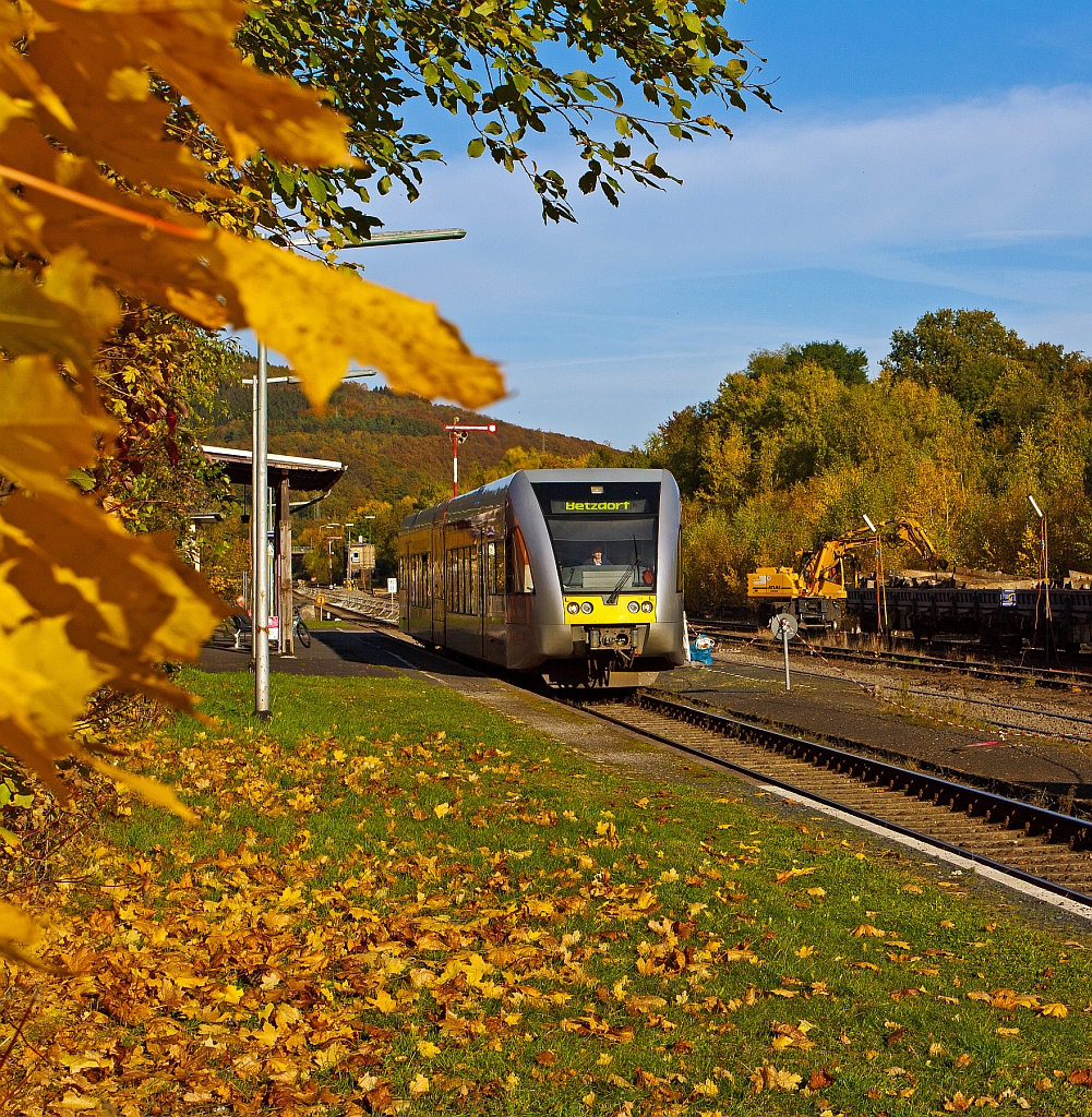 Ein Stadler GTW 2/6 der Hellertalbahn f�hrt am 18.10.2012 vom Bahnhof Herdorf weiter in Richtung Betzdorf/Sieg. Im Hintergrund verl�d ein Atlas Zweiwegebagger alte Schellen auf Res-Wagen.
