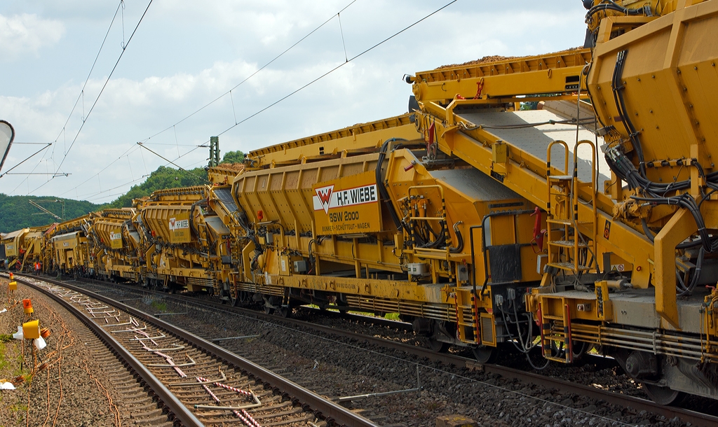 Ein weiterer Blick in Richtung Planumsverbesserungsmaschine RPM W 2002 – 2 der GBM Wiebe Gleisbaumaschinen GmbH (Arbeits- und Materiallaufrichtung), am 13.07.2013 bei Katzenfurt (Lahn-Dill-Kreis) an der KBS 445 (Dillstrecke).

Hier die BSW 2000 Bunker-Schuttgut-Wagen (Bezeichnung von Wiebe) sind eigentlich von Plasser & Theurer gebaute Materialf�rder- und Siloeinheiten MSF 38.

Technische Daten:
L�nge �ber Puffer: 19.900 mm
Gesamtl. m. �bergabeband: 23.550 mm
Breite:  2.894 mm
H�he:   3.850 mm
Eigengewicht:  38,5 t
Zuladung:  51,5 t bzw. 38 m�
Anzahl der Achsen:  4 (in zwei Drehgestellen)
Motor:  Deutz F 5 L 912 Dieselmotor f�r die Erzeugung der hydraulischen Energie
Motorleistung:  ca. 60 kW 
V max. Zugverband:  100 km/h
