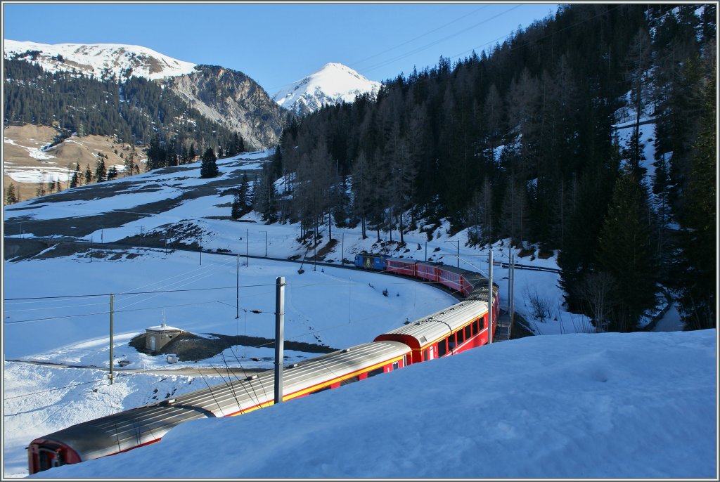 und  f�hrt nun bis zum n�chsten Kehrtunnel nordw�rts. 
Der Zug wird etwa f�nf Minunten sp�ter auf der obersten Stufe durch den Wald im rechten Bildteil weiter zur Dienststation Mout (1575 m�M) fahren und dannach zahlreiche Br�cken und Kehrtunnel in verschlungener Linienf�hrung Preda (1789 m�M) und damit den Albula Tunnel erreichen.
16. M�rz 2013