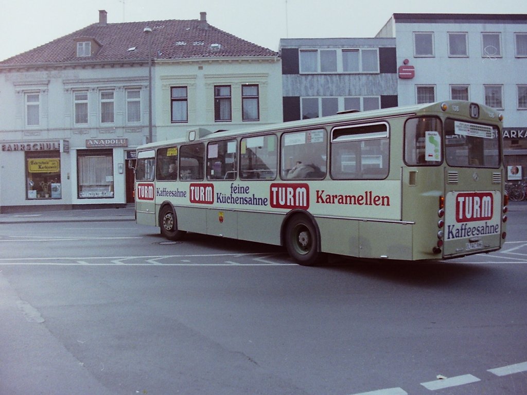 Wagen 136, OL-AC 886, EZ: 1974. Im Juni 1982 erhielt Wagen 136 eine neue Version der bisherigen TURM-SAHNE-Werbung. Auf diesem Bild kommt der Bus aus der Lindenstra�e, die er entgegen der Einbahnstra�e befahren hatte, und quert die Gertrudenspinne. Die Aufnahme entstand am 02.10.82 w�hrend des Kramermarktumzuges. Der Bus war, wie fast alle O 305 zu diesem Zeitpunkt, bereits am Heck oben mit runden Blinkern ausgestattet. Die eckigen, urspr�nglich waagerecht angebrachten Originalblinker, waren h�ufig in der Waschanlage besch�digt worden.