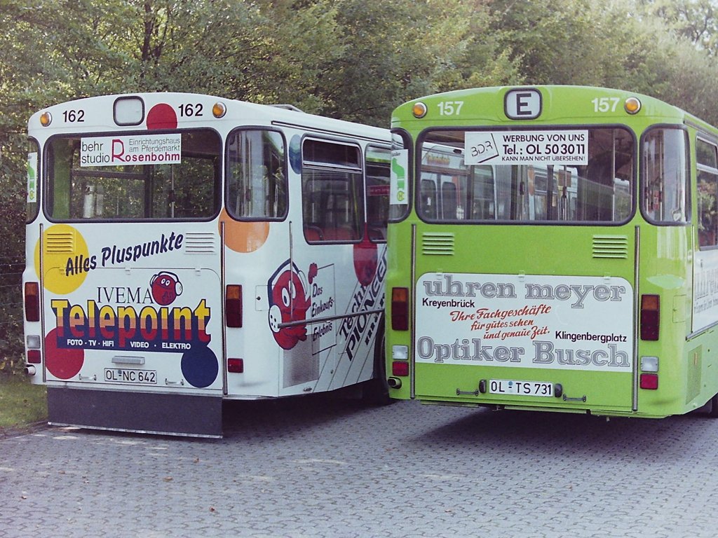 Wagen 157. Rolle r�ckw�rts ! Der ehemalige gr�ne Wagen 162 war zwischenzeitlich wie bereits beschrieben mit Vollwerbung unterwegs, der ehemalige ganzlackierte Bus 157 nun wieder gr�n. Hier auch gut zu erkennen: Der j�ngere Wagen 157 hat zwei R�ckfahrscheinwerfer. An beiden Bussen fehlt der Mercedesstern. Wagen 162 hat die nicht so beliebte Form der Kennzeichenbeleuchtung �ber dem Kennzeichen, w�hrend bei Wagen 157 die Beleuchtung links und rechts neben dem Kennzeichen angebracht ist. Wagen 162 wurde nachtr�glich mit einer Sch�rze ausgestattet, die das Aufwirbeln von Schmutz auf die Werbefl�che verhindern soll. Und ein weiteres Detail, dass aber so kaum zu sehen ist ...