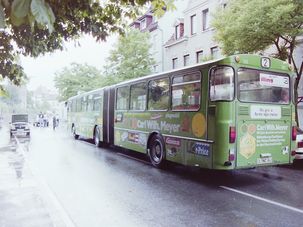 Wagen 161, OL-NC 641, EZ: 1980, FIN 30710013026114. Jahrelang beherrschten MAN Gelenkbusse dieses Segment des �ffentlichen Personennahverkehrs. Dabei war die Bauweise relativ einfach. Der sogenannte Nachl�ufer wurde auf den Vorderwagen aufgesattelt und zwischen den beiden Fahrzeugteilen eine Drehscheibe und die sogenannte Ziehharmonika gesetzt. Der Antrieb erfolgte �ber die zweite Achse. Erst mit der Entwicklung einer Steuerung, die verhinderte, dass sich der Bus �ber einen bestimmte Winkel hinaus knickte, war es m�glich Fahrzeuge herzustellen, deren Motor wie bei einem Solowagen im Heck sa�en und ihren Antrieb auf die letzte Achse �bertrugen. Daimler Benz hatte die Rechte an dieser Entwicklung erst Ende der 70ziger Jahre erhalten und so waren Wagen 162 und 161, als sie am 14.11.80 den Betriebshof erreichten, die ersten Daimler Benz Gelenkbusse in Oldenburg. Deutlich ist auf dem Bild die Klappe im Fahrzeugheck zu erkennen, untr�gliches Zeichen f�r den dahinter eingebauten Motor. Da also die letzte Achse den Bus praktisch anschob, sprach man von Schubgelenkbussen. Auf dem Foto steht Wagen 161 nach einem heftigen Regengu� im Juli 1992 vor einer Polizeiabperrung in H�he des Gertrudenfriedhofes. Der Bus war mit dieser Werbung in seiner gesamten Dienstzeit im Einsatz. Die Werbung wurde in dieser Zeit nur geringf�gig ver�ndert. 