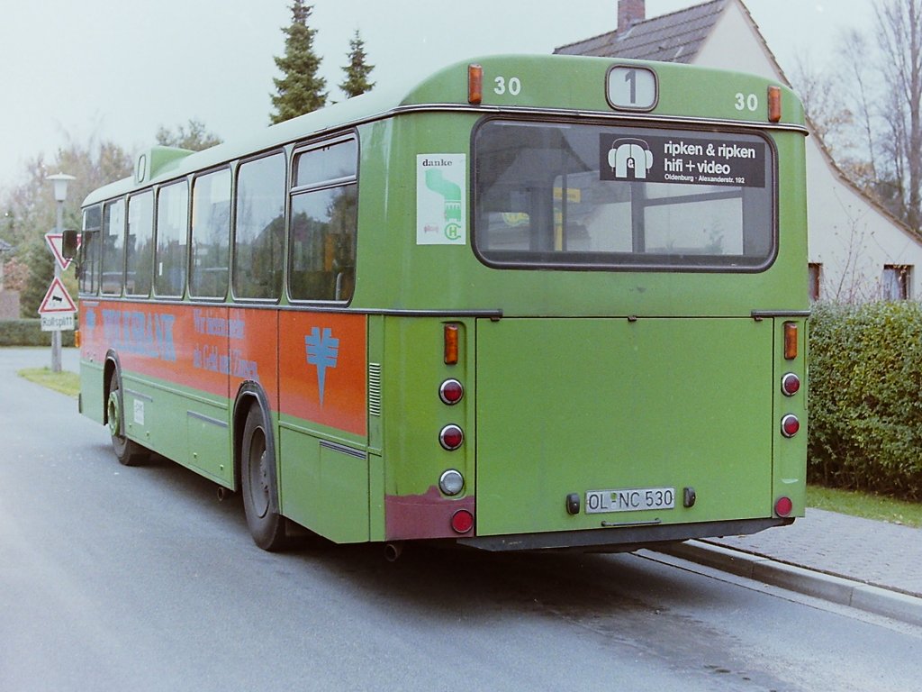 Wagen 30, OL-NC 530, EZ: 1978. Als dieses Bild im Oktober 1987 entstand, hatte der Bus bereits Einiges hinter sich. Aktuell war die Heckklappe zwar nach einem Schaden getauscht, aber noch nicht mit Werbung versehen. Der linke Teil des Hecks ist bereits gerichtet und im unteren Bereich schon wieder gespachtelt und vorbereitet f�r eine Lackierung. Unter dem Werbeband auf der Fahrerseite sind gut die horizontalen Leisten zu erkennen. Auch sie deuten auf Ausbesserungsarbeiten an der Flanke des Busses hin. Ort der Aufnahme ist die Endstation der Linie 1 AM STADTRAND.
