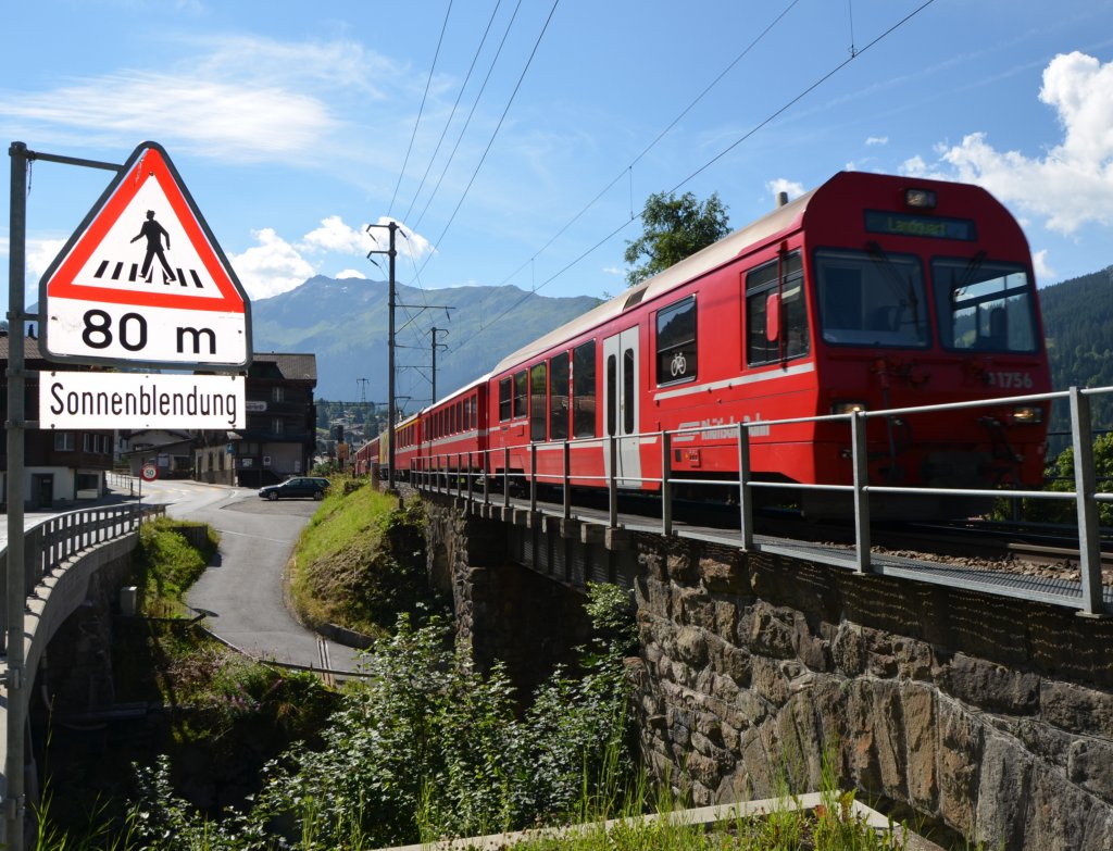 Zug von Scuol-Tarasp nach Landquart kurz hinter dem Bahnhof Klosters Dorf.
Das linke Schild warnt offensichtlich vor tiefstehender Morgensonne (von links hinten). Der besondere Effekt ist aber offensichtlich durch den Blitz hervorgerufen.
(Aufnahme 10.08.2012)