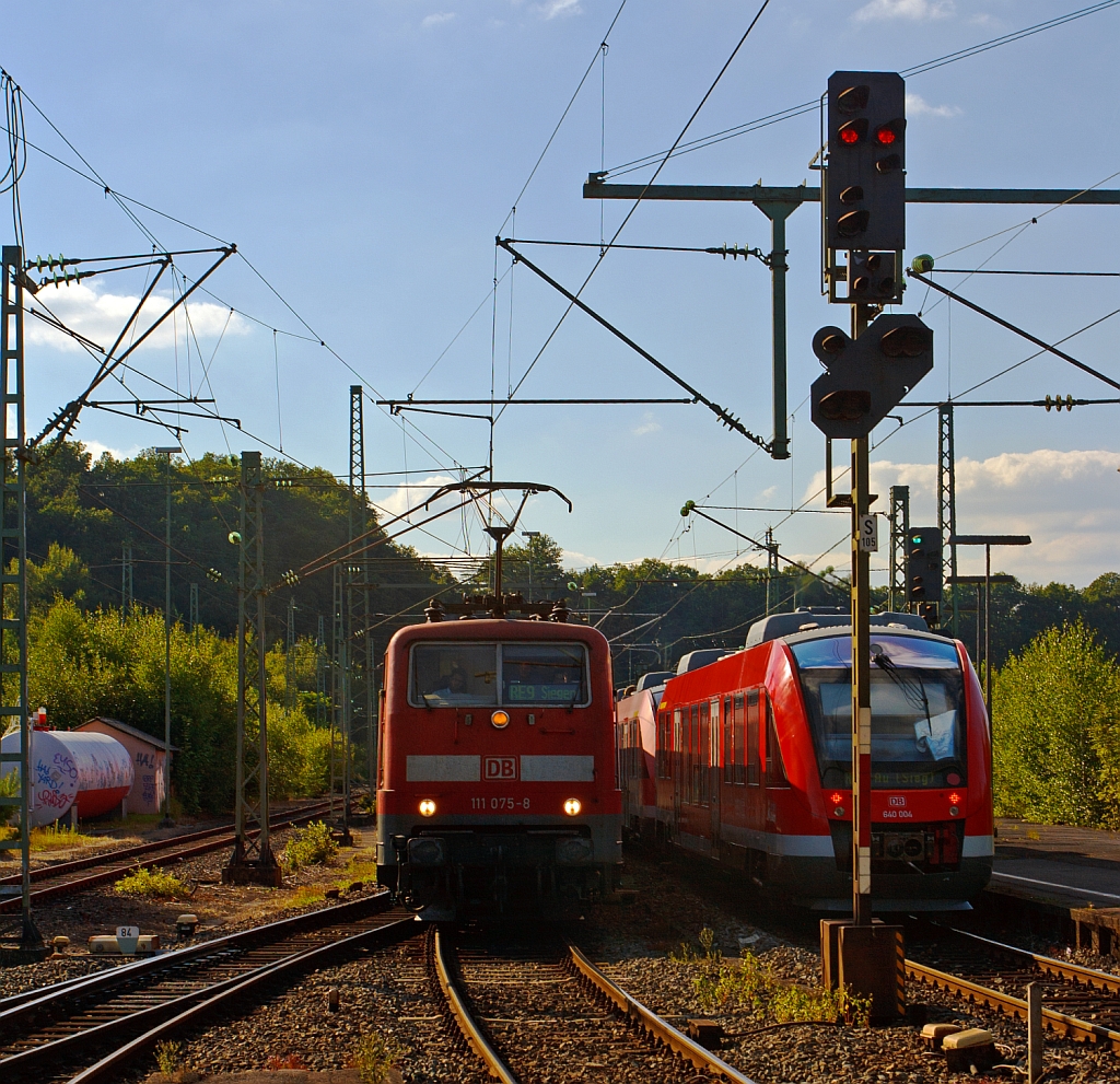 Zugbegenung in Betzdorf (Sieg) am 10.08.2012 - Links f�hrt der RE 9 (Rhein-Sieg-Express) Aachen - K�ln - Siegen ein mit Zuglok 111 075-8, Rechts f�hrt die RB 95  (Dillenburg - Siegen - Betzdorf - Au/Sieg ) zwei gekuppelte  LINT 27 (640 028 und 640 004) weiter in Richtung Au (Sieg). Hier mit starkem Streiflicht.
