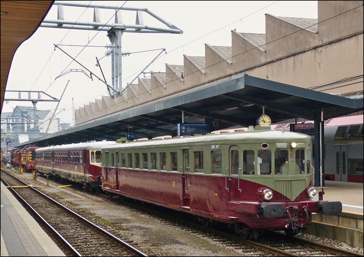 . Der restaurierte Diesel Triebzug Z 105 war am 12.10.2013 im Bahnhof von Luxemburg Stadt ausgestellt. (Hans)

Die CFL Baureihe Z 100 wurde im Jahre 1949 von den De Dietrich Werken (Reichshoffen / Frankreich) an die CFL geliefert und ist identisch mit der Baureihe X 3700 der SNCF. Die zehn De Dietrich leisteten ab 1950 ein Drittel der j�hrlichen Personenzugkilometer der CFL (�100.000 Kilometer pro Triebwagen). Alterserscheinungen anfangs der siebziger Jahre des 20.Jahrhunderts f�hrten zur Abstellung verschiedener Triebwagen. Am 27. Mai 1978 wurden dann die verbliebenen Triebwagen durch einen Beschluss des CFL Verwaltungsrates ausgemustert. Dennoch gingen nicht alle Triebwagen sofort den Weg des alten Eisens. So wurde der Triebwagen Z 105 1978 vom GAR (Groupement des Amis du Rail) erstanden und im BW Luxemburg hinterstellt.

Z 105 ist seit 1992 wieder einsatzf�hig und hat seither mehrere Tausend Kilometer auf luxemburgischen und ausl�ndischen Gleisen absolviert. Fahrten 1997 zum Jubil�um der SBB, 1998 nach Paris und Tours (F) zu einer Retrospektive des Triebwagenbaus in Frankreich geh�ren zweifellos zu den pr�gendsten Fahrten des Schienenoldies.

Leider ist die Betriebserlaubnis von Z 105 seit Oktober 1999 erloschen, da die direktt�tige Bremse Bauart Westinghouse nicht mehr zugelassen ist. Der Triebwagen Z 105 geh�rt seit Mitte des Jahres 2001 dem staatlichen Denkmalschutzamt (Service des Sites et Monuments Nationaux). Am 12.September 2001 erfolgte die �berf�hrung des Triebwagens Z 105 in die Werkst�tten von CFD-Locorem in L�ttich und Mecanofer in Janneyrias (F), sowie bei den Arriva-Werken-Nord in Neustrelitz (D) zwecks Einbau von GSM-R und Zugsicherung. Hier wird, im Auftrag des staatlichen Denkmalschutzamtes, der Triebwagen einer grundlegenden Modernisierung (Bremse, Motoren, Drehgestelle) unterzogen.

Technischen Eigenschaften des Z 105: Der Triebwagen hat eine L�nge �ber Puffer von 25,81 Metern, ist in fahrbereitem Zustand 34 Tonnen schwer und bot anfangs 20 Personen in der 2. Klasse und 55 Personen in der 3. Klasse Platz. Zus�tzlich standen noch 20 Stehpl�tze zur Verf�gung. Die 2./3. Klasse Aufteilung wurde 1956 in eine reine 2. Klasse Ausf�hrung umgewandelt. Um den Fahrg�sten auch im Winter ein geheiztes Obdach zu gew�hren, verf�gt der Triebwagen �ber ein autonomes Heizsystem mittels eines Koksofens welcher die Warmwasserheizung des Passagierraumes heizt. Angetrieben wird der Triebwagen von 2 SAURER-Dieselmotoren des Typs BXDS, welche �ber eine Nennleistung von je 160 PS bei 1500 Umdrehungen / Minute verf�gen. Die Leistung der Dieselmotoren wird mittels einer Kupplung �ber zwei mechanische Vierganggetriebe Bauart Mylius CV 2 an die Hinterachse eines jeden Drehgestells gebracht. Kupplung und Motorsteuerung werden pneumatisch bet�tigt; die Getriebe werden �ber Bowdenz�ge geschaltet. Diese etwas eigenartige Antriebsweise verleiht dem Triebwagen ein exzellentes Beschleunigungsverm�gen, wodurch die H�chstgeschwindigkeit von 120 km/h schnell erreicht wird. Der Triebwagen wird mittels einer direktt�tigen Luftdruckbremse Bauart Westinghouse, welche �ber eine einzigartige Bremsleistung verf�gt, abgebremst. 