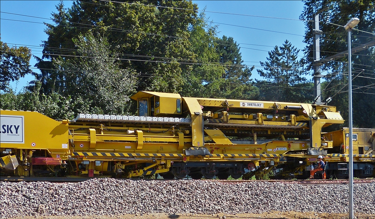 . Detailfoto des Gleisumbauzuges. Der Schwellentransportschlitten legt die in der Mitte des Zuges geholten Betonschwellen auf das Transportband der Schwellenlegemaschine.  Schieren  06.08.2016