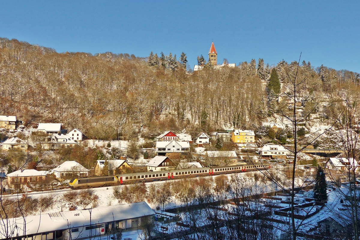 . Winter in Clervaux - Die Fotostelle in der  Welzerstrooss  in Clervaux bietet nur noch sehr wenige M�glichkeiten den Zug unverdeckt abzulichten. Die leider auch sehr schmutzige 3013 mit dem IC 110 Liers - Luxembourg am Haken f�hrt unter der Benediktiner Abtei St Maurice am Campingplatz in Clervaux vorbei. 28.12.2014 (Jeanny)