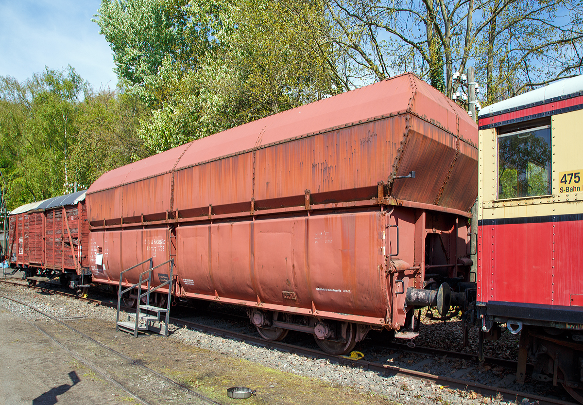 
00t 24 DR Selbstentladewagen 2233 Oldenburg, sp�ter DB 20 80 676 0139-2 der Gattung Fad 150, am 30.04.2017 im Eisenbahnmuseum Bochum-Dahlhausen.
Eine Wagengattung die bis Mitte der 1960er Jahre, durch den Erzbergbau und die Eisenverh�ttung, auch das Bild im Hellertal gepr�gt hatte. Daher besa� auch der Bahnhof Herdorf �ber 10 Gleise (DB), plus die Gleise der Friedrichsh�tte und der Freien Grunder Eisenbahn.

Die fortschreitende Industrialisierung erforderte den Transport immer gr��erer Mengen von Masseng�tern, zum Teil auch �ber gr��ere Entfernungen. Beispielhaft seien die Kohletransporte aus Schlesien oder dem Ruhrgebiet. Sowie die Erztransporte von den Nordseeh�fen, aber auch den deutschen Erzrevieren wie dem Siegerl�nder Erzrevier oder dem Salzgitterrevier zu den Industriebetrieben. Die erforderlichen Masseng�ter zur Stahlerzeugung, namentlich Kohle, Koks, Kalk und Erz wurden zunehmend in Ganzz�gen transportiert, d.h. alle G�terwagen eines Zuges waren mit dem gleichen Ladegut beladen und fuhren meist zu einem Zielort. Da die �blichen offenen G�terwagen nur 15 bis 20 Tonnen Fracht transportieren konnten, waren h�ufige Fahrten notwendig, wozu eine entsprechende Anzahl Wagen und nat�rlich auch Lokomotiven mit entsprechendem Personalaufwand notwendig waren.

Der kontinuierliche Ausbau der Eisenbahnstrecken f�r schwerere Fahrzeuge ebnete den Weg zur Entwicklung der Gro�raumg�terwagen. Die Selbstentladetechnik erm�glichte ein mechanisiertes Be- und Entladen der Wagen unter Ausnutzung der nat�rlichen Schwerkraft. Ebenso waren f�r die gleiche Transportleistung weniger Wagen, weniger Lokomotiven und somit auch weniger Personal- und Reparaturaufwand erforderlich. Ab Mitte der 1920er Jahre wurden die ersten Selbstentlade-Gro�raumg�terwagen der Gattung 00t(n) durch die Deutsche Reichsbahn beschafft. Bei einer L�nge von 12 m konnte der hier gezeigte Wagen Oldenburg 2 233 rund 56 t Ladegut transportieren. Dazu waren fr�her 3 bis 4 normale offene G�terwagen notwendig, die zusammen eine L�nge von 30 bis 40 Metern erreichten!

Das hohe Ladegewicht erforderte vier Rads�tze, die mit bis zu 20 t belastet wurden. Sie wurden bei diesem ersten Gro�raumwagentyp aber noch nicht wie heute �blich in Drehgestellen, sondern paarweise als freie Lenkachsen eingebaut. Die Achsen haben in ihren durch eiserne Streben versteiften Achsf�hrungen Seiten- und L�ngsspiel und erm�glichen ein verschlei�vermindertes Durchfahren von Kurven, da sich die Rads�tze radial einstellen k�nnen. Ein weiterer Fortschritt war die Anwendung einer automatischen Scharfenbergkupplung. So konnte die Zugbildung vereinfacht werden, da mit dieser Bauart das Kuppeln selbstt�tig erfolgte. Mit einer Notkupplung kann mit normalen Kupplungen gekuppelt werden. 
TECHNISCHE DATEN:
Selbstentladewagen Deutsche Reichsbahn
Bauart: 00t 24 
Baujahr: 1930
Hersteller: O&K, Berlin-Spandau
L�nge �ber Puffer: 12.000 mm
Eigengewicht: 22,3 t
max. Ladegewicht: 56.0 t
max. Gesamtgewicht: 78,3 t
Ladevolumen: 92 m�
H�chstgeschwindigkeit: 65 km/h
Fahrgestell und Wagenaufbau aus Stahl (Bleche aus St 52), genietet

