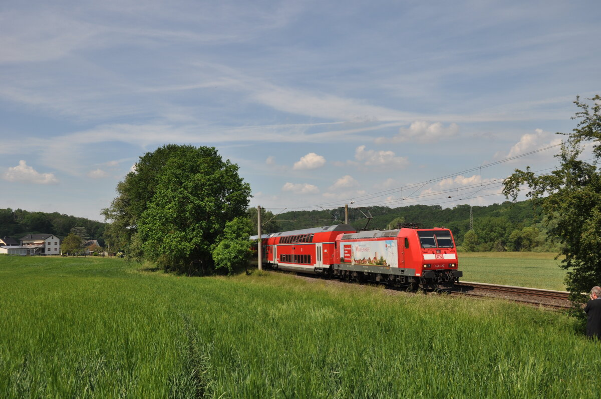 146 127  Marienhafe  ist hier auf ihrer ersten Fahrt für DB Regio Hessen am 11.06.2021 in Lindenholzhausen zu sehen, sie ist als RB22 nach Frankfurt Hbf unterwegs.
Die Lok wurde kurzfristig eingesetzt, da 146 126 an diesem Tag eine Störung hatte und abgeschleppt werden musste. Eine 143 wollte man wohl nicht mehr in dem Umlauf schicken.
Vielleicht überlegte sich ja der ein oder andere Fahrgast bei Anblick der Lok den Erholungsort  Marienhafe  mal aufzusuchen. :-) 