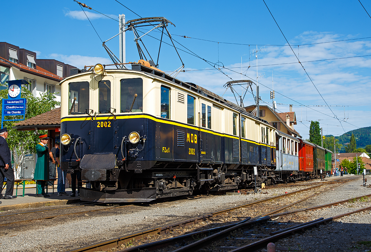 
50 Jahre BC - MEGA STEAM FESTIVAL der Museumsbahn Blonay–Chamby:
Bevor wir nach Vevey herunter „surften“...
Konnten wir noch im tollen Morgenlicht den wunderschöne Gelenktriebwagen ex MOB DZe 6/6 2002, bzw. FZe 6/6 2002 bestaunen und fotografieren. Hier steht er am 21.05.2018 im Bahnhof Blonay mit einem Zug zur Abfahrt zum Museum bereit.

Der Triebwagen Gepäck- und Postabteil wurde 1932 von SIG unter der Fabriknummer 3703 gebaut, der Elektrische Teil ist von BBC. Der Gepäcktriebwagen wurde 1996 in der Remise Gstaad Abgestellt und gedamelte vor sich hin, bis er im Juli 2008 zur Museumsbahn Blonay–Chamby ging.

Die MOB (Montreux–Berner Oberland-Bahn) beschaffte für die Bespannung des “Golden Mountain Pullman Express” die beiden zweiteiligen Gelenktriebwagen FZe 6/6 2001 und 2002 (MOB-intern immer „Lokomotiven“ bzw. „Gepäcklokomotiven“ genannt). Nachdem der Expresszug schnell wieder eingestellt wurde (vor der Lieferung), fanden die beiden Gelenktriebwagen ein neues Betätigungsfeld im schweren Schnellzug- und Güterzugverkehr bzw. bespannten Sonderzüge mit den bei der MOB verbliebenen Salonwagen.

Riesig sind sie, mit immerhin 17 m Länge, sind diese Gelenktriebwagen eine eindrucksvolle Erscheinung. Bis zur Einführung der Baureihe GDe 4/4 6000, also rund fünfzig Jahre lang, waren sie außerdem mit ihren rund 1.000 PS die leistungsstärksten Gleichstrom-Lokomotiven der Schweiz. 

Die ursprüngliche Bezeichnung war „FZe 6/6“ (Triebwagen mit Gepäck- (F) und Postabteil (Z)) wurde später in „DZe 6/6“ geändert. Eine solche Umzeichnung fand europaweit irgendwann nach dem 1. Januar 1962 statt, sie entsprach dem RIC-Reglement (Regolamento Internazionale Carrozze, ein Übereinkommen über die gegenseitige Benutzung der Personen- und Gepäckwagen im internationalen Verkehr). 

Die beiden Fahrzeuge 2001 und 2002, trugen nie irgendwelche Wappen oder Namen, sie behielten allerdings bis heute die Pullman-Lackierung in dunkelblau/crème mit gelbem Seitenstreifen

TECHNISCHE DATEN:
Fahrzeugbezeichnung: DZe 6/6 bzw. (FZe 6/6)
Anzahl Fahrzeuge: 2  (2001 und 2002)
Inbetriebsetzung: 1932
Spurweite: 1.000 mm
Achsanordnung: Bo'Bo'Bo' 
Dienstgewicht: 62,8 t
Länge über Kupplung: 17.000 mm
Kastenlänge: 2 x 7.850 mm
Fahrzeughöhe: 3.550 mm
Fahrzeugbreite: 2.700 mm
Drehgestellabstand: 2 x 5.500 mm
Achsabstand im Drehgestell: 2.300 mm
Treibraddurchmesser (neu): 945 mm
Höchstgeschwindigkeit: 55 km/h
Maximale Leistung am Rad 	6 x 132 kW = 738 kW	
Getriebeübersetzung: 1:6.94
Ladefläche Gepäck- / Postraum: 10 m² / 8 m²	 (4t)
Stromsystem: 900 V DC

