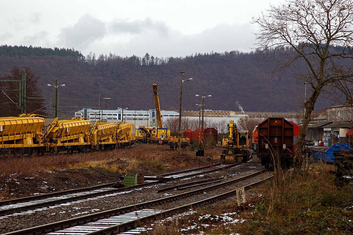 Am 08.12..2021 ist in Scheuerfeld (Sieg) beim Kleinbahnhof der WEBA (Westerwaldbahn) viel los. Erst dachte ich es sei einen Gro�baustelle, dann vielleicht ist auch was entgleis. Nein es war doch ganz anders.

Links steht die 202 466-9 (nicht im Bild) mit einem Materialf�rder- und Siloeinheiten-Zug der (MFS 38, sowie Beladestation) der HERING Bahnbau, mit dem Ziel Betriebshof der WEBA auf der Bindweide (Steinebach/Sieg). Die V 100 ost der SKL Umschlagservice Magdeburg mit dem Zug noch warten, da rechts die KSW 44 (271 004-4) die MaK G 1000 BB der Kreisbahn Siegen-Wittgenstein noch einige Holzwagen rangiert. Das linke Ausweichgleis, auf dem der ATLAS 1604 ZW Zweiwegebagger der WEBA (Kleinwagen Nr. D-WEBA 99 80 9901 645-9) steht, ist zudem gesperrt. 

In der Bildmitte, zwei Gleiskrane der HERING Bahnbau GmbH (Burbach). Der mit dem gehobenen Kranausleger ist der 125t Gleisbauschienenkran - KIROW Multi Tasker KRC 910, Schweres Nebenfahrzeug Nr. 99 80 9419 014-2 D-HGUI,  Thor . Der  Thor  nimmt derzeit das Gegengewicht, von dem 125t Gleisbauschienenkran KIROW Multi Tasker KRC 810 T, Schweres Nebenfahrzeug Nr. D-HGUI 99 80 9419 024-1, an den Haken, da es demontiert werden muss. Vermutlich ist die Demontage des Gegengewichtes n�tig, damit der Kran leichter wird, denn auch er soll zur WEBA nach Steinebach/Sieg auf die Bindweide. Der Kran hat eine Radsatzlast in Transportstellung von 18,2 t, aber wichtige Meterlast in Transportstellung von 9,85 t/m, diese Meterlast (Streckenlast) d�rfte f�r die WEBA Strecke (Scheuerfeld – Bindweide) zu hoch sein. Denn die Strecke hat zwischen Scheuerfeld und Elben die Streckenklasse D4 (Achslast 22,5 t, Meterlast 8 t/m) und zwischen Elben und Bindweide nur noch die Streckenklasse C2 (Achslast 20 t, Meterlast 6,4 t/m). Bis 2020 war die Strecke noch durchg�ngig D4. 