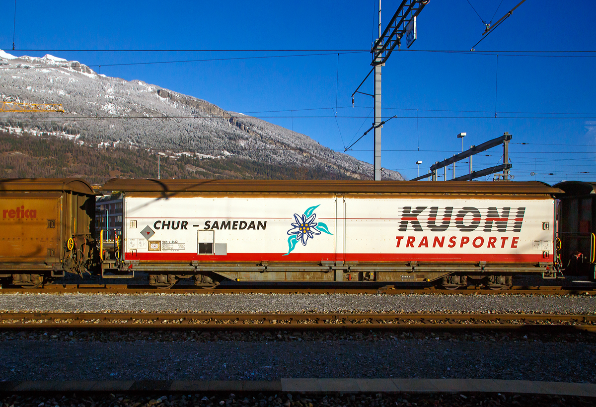 Aus dem Zug heraus....
Der gedeckte vierachsige RhB-Schiebewandwagen Haik-v 5131 „Gebr. Kuoni Transport AG“ am 18.02.2017 in Chur.

Der gedeckte vierachsige Schiebewandwagen des Typs „Haik“ ist ein idealer G�terwagen f�r den Transport von 31 Normpaletten mit Lebensmitteln, Getr�nken, Baustoffen und allen anderen G�tern. Die Schiebwand �ffnet sich auf einer Breite von �ber 6 Metern, um nach dem Beladen mit Handhubwagen oder Gabelstapler das Transportgut wieder komplett zu sch�tzen, vor Wetter und Temperatureinfl�ssen.

TECHNISCHE DATEN:
Typenbezeichnung:  Haik-v
Baujahr:  1980
Spurweite: 1.000 mm
L�nge �ber Puffer: 14.695 mm 
Drehzapfenabstand: 9.030 mm 
Achsabstand im Drehgestell: 1.400 mm
Raddurchmesser (neu): 750 mm
Ladel�nge: 14.755 mm
Ladebreite:  2.580 mm
Ladefl�che: 32.7 m� 
Eigengewicht: 15.300 kg
Ladegewicht:  26 Tonnen
H�he der Ladefl�che ab Schienenoberkante: 975 mm
