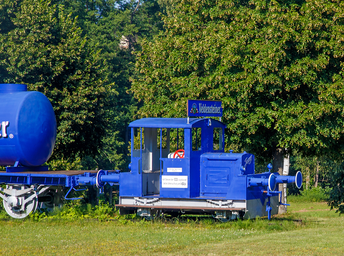 
Aus einem vorbeifahrenden Zug heraus durch die Scheibe fotografiert....
Auf dem Betriebsgel�nde der Kaiser Br�u in Neuhaus a.d.Pegnitz (01.07.2015) steht als Denkmal ein Jung Rangierschlepper ZN 113.

Die kleine normalspurige Rangierlok bzw. Jung Rangierschlepper vom Typ ZN 113 wurde 1941 von der Arnold Jung Lokomotivfabrik GmbH  in Jungenthal bei Kirchen/Sieg unter der Fabriknummer  9911 gebaut an S�gewerk Leonhard Prass in Neuhaus a .d. Pegnitz geliefert.  Im Jahr 1989 wurde das S�gewerk geschlossen und die Kaiser Br�u oHG (Veldensteiner ) �bernahm das Betriebsgel�nde wie auch die Lok, die 1992 endg�ltig stillgelegt und als Denkmal aufgestellt wurde. Etwa 2010 wurde die historische Lokomotive von dem Brauereiteam aufgearbeitet und in den Veldensteiner-Farben lackiert, leider nicht in der originalen Farbgebung.

Technische Daten:
Spurweite: 1.435 mm
Achsformel: B
Dienstgewicht: 8 t
Motor: Jung Zweizylinder-Zweitaktdieselmotor vom Typ SZ 110 (Stehender Einzylinder Zweitaktmotor mit einem Kolbendurchmesser von 110 mm)
Leistung: 22 bis 24 PS
Nenndrehzahl: 1.000 U/min
H�chstgeschwindigkeit: 8 - 12 km/h

Die bekannte Lokfabrik Jung in Jungenthal, Kirchen a.d. Sieg, hatte anfangs haupts�chlich Dampflokomotiven f�r Feld, Schmalspur- und Vollbahnen hergestellt, baute aber schon in den 1920er Jahren f�r dieselben Einsatzbereiche Dieselloks in gro�er St�ckzahl, f�r die �berwiegend eigene Motoren und Getriebe verwendet wurden. 

Aufbauend auf die vorhandenen Konstruktionen aus der Feldbahnfertigung wurden auch kleine Rangierschlepper in Normalspur geliefert, die auf Anschlussgleisen von Industriebetrieben Verwendung fanden.

Einer der kleinsten Typen im Lieferprogramm von Jung war der Diesel-Verschiebebock  ZN 113  mit ca. 8 t Dienstgewicht und 22-24 PS Leistung. Der Schlepper hat einen Jung Zweizylinder-Zweitaktdieselmotor vom Typ SZ 110 (Stehender Einzylinder Zweitaktmotor mit einem Kolbendurchmesser von 110 mm) mit 22-24PS Leistung bei 1.000 U/min. Diese Motoren baute Jung selbst und waren bei richtiger Pflege unverw�stlich. Die Leistungs�bertragung erfolgte von einem mechanischen Dreiganggetriebe �ber Rollenketten auf beide Achsen. Der Schlepper besa� serienm��ig kein F�hrerhaus - nur eine offene Plattform. Die erreichbare H�chstgeschwindigkeit lag bei 8 - 12 km/h, die Zugkraft reichte f�r 2-4 beladene G�terwagen in der Ebene aus. Einige dieser Jung-Schlepper sind noch heute bei Museumsbahnen zu finden.

