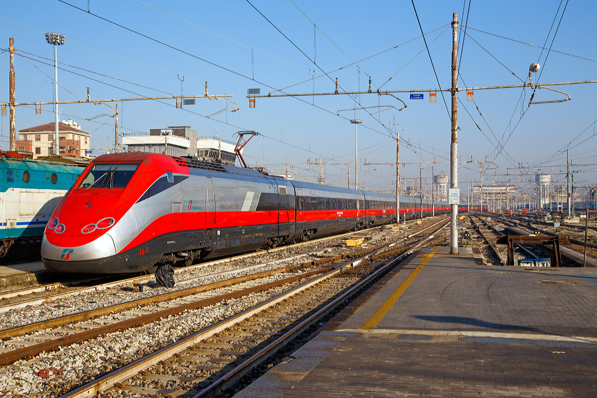 Ausfahrt eines sehr langen  Frecciarossa  (deutsch: roter Pfeil) der Trenitalia (100-prozentige Tochtergesellschaft der Ferrovie dello Stato) am 29.12.2015 vom Bahnhof Milano Centrale (Mailand Zentral). Der Frecciarossa ist eine Zuggattung für Züge mit einer Höchstgeschwindigkeit von 300 km/h. Hier ist es der ETR 500 - 56 ein ETR 500 der 2.Serie. ETR steht ElettroTreno Rapido.

Diese Züge bestehen aus zwei Triebköpfen vom Typ E.404B und aus zwölf Mittelwagen, ETR 500.31 bis 60 komplett der 2.Serie. Bei den ETR 500.01 bis 30 sind nur die beiden Triebköpfe aus der 2.Serie, die Mittelwagen dagegen stammen aus der 1.Serie der ETR 500 (Mono). 

Durch die begrenzte Stromstärke des Gleichstromnetzes können die Hochgeschwindigkeitszüge nur für Geschwindigkeiten bis zu 250 km/h ausreichend mit Energie versorgt werden. Deshalb entschied sich die italienische Staatsbahn in den 1990er Jahren, weitere Neubau-Schnellfahrstrecken mit Wechselstrom (25 kV, 50 Hz) zu betreiben.

Da die erste Serie der ETR 500 nur für das Gleichstromnetz geeignet ist, wurde ab 1996 eine zweite Serie ETR 500 bestellt und geliefert, die sowohl im Gleichstrom- als auch im Wechselstromnetz fahren kann. Die Zweisystem-Fahrzeuge werden Politensione (deutsch: Mehr-Spannung) genannt. Es gab auch mal zwischenzeitlich Dreisystem-Fahrzeuge (ETR 500 F), die auch unter 1.5 kV DC fahren konnten, diese wurden aber wieder zurückgebaut. Diese waren für den Verkehr nach Frankreich gedacht, bekamen aber dort keine Zulassung.

Die zulässige Höchstgeschwindigkeit der ETR 500 der zweiten Serie von 300 km/h wird im regulären Betrieb aber nur mit Wechselstrom auf neueren Schnellfahrstrecken Italiens erreicht.

Im Gegensatz zur ersten Serie werden bei der zweiten Serie Einholmstromabnehmer verwendet. Die Triebköpfe verfügen jeweils über einen Abnehmer für Gleichstrom und einen Abnehmer für Wechselstrom. Äußerlich unterscheiden sich die beiden Bauserien durch starke Unterschiede des „Gesichts“. Die Front der zweiten Serie wurde aufgelockert und rundlicher gestaltet, besonders betont durch die getrennt angeordneten Spitzensignale, während die Frontscheiben kleiner und rechteckig ausgeführt wurden. Wobei ja die Triebköpfe (E.404A) der ersten Serie zu Lokomotiven der Baureihe E.414 umgebaut wurden.


TECHNISCHE DATEN:
Von einem Triebkopf E.404B
Spurweite:  1.435 mm (Normalspur)
Achsformel: Bo'Bo'
Länge: 20.250 mm
Höhe: 4.000 mm
Breite: 3.020 mm
Drehzapfenabstand:  11.450 mm
Achsabstand im Drehgestell: 3.000 mm
Dienstgewicht: 68 t
Höchstgeschwindigkeit: 300 km/h
Dauerleistung: 4.400 kW (4 x 1.100 kW) pro Triebkopf
Treibraddurchmesser:  1.100 mm
Stromsysteme: 3000 V DC und 25 kV 50 Hz AC

Daten der Mittelwagen:
Länge: 26.100 mm
Drehzapfenabstand:  19.000 mm
Achsabstand im Drehgestell: 3.000 mm
Eigengewicht: 40 t

Gesamtzug Daten:
Achsformel: Bo'Bo' (12x 2'2') Bo'Bo'
Gesamtzuglänge: 353.700 mm (bei 12 Mittelwagen)
Gesamteigengewicht: 616 t
Dauerleistung: 8.800 kW
Anfahrzugkraft:  400 kN