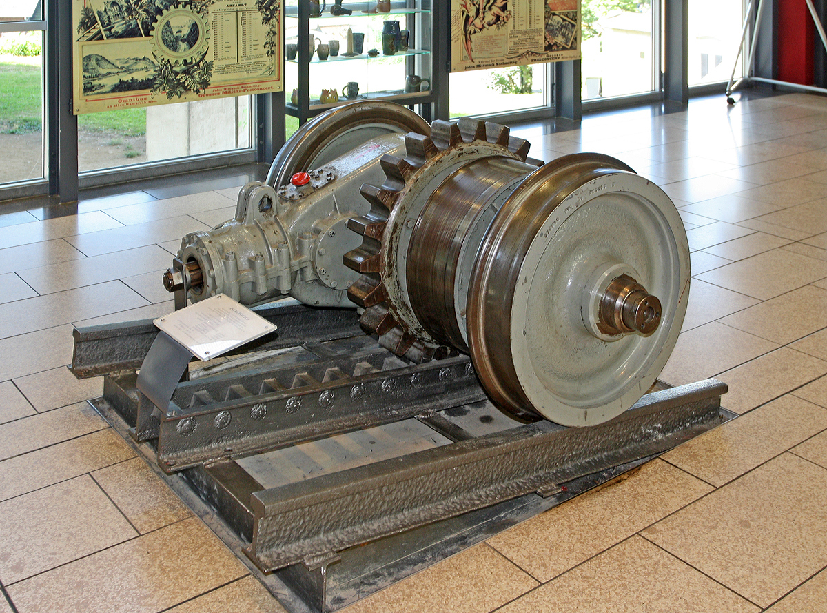 Ausgestellt im Empfangsgeb�ude der Talstation Drachenfelsbahn am 06.06.2014 in K�nigswinter:
Antriebsachse mit Getriebe, Hauptantriebszahnrad und Bremstrommel der Klinkenbandbremse. Konstruiert durch die Firma BBC im Jahr 1956, hergestellt von der Firma Kl�ckner-Humbold-Deutz AG. 

Technische Daten: 
Gewicht: 1,4 t 
Laufleistung: ca. 320.000 km 
Z�hnezahl Antriebszahnrad: 22 
Getriebe�bersetzung: 1:18,88 
Laufraddurchmesser: 666 mm 
Spurweite: 1.000 mm 
Zahnstangensystem: Riggenbach, 100 mm Zahnabstand