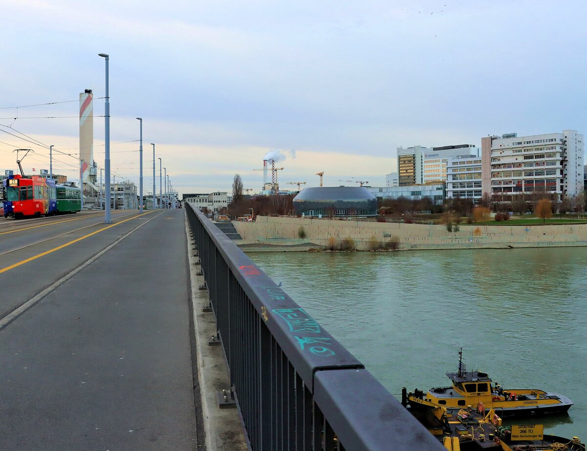 Bald endet der Einsatz von Vierachsern in Basel: Blick auf den Rhein von der Dreirosenbrücke, hin zum grossem Campus des Chemiekonzerns Novartis. Ganz links kommt Motorwagen Be 4/4 490 mit Anhänger 1487 vom Bahnhof St.Johann her. 7.Dezember 2021 