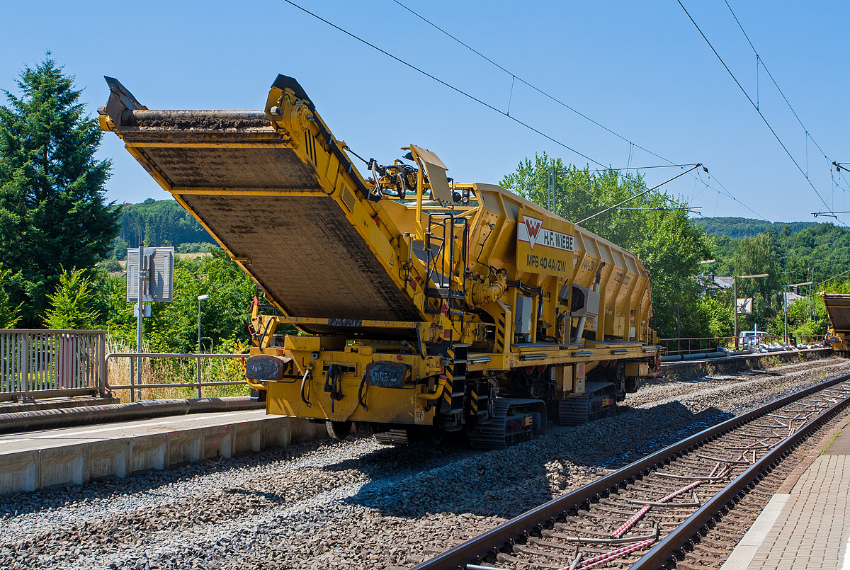 Baustelle im Bahnhof Katzenfurt (Lahn-Dill-Kreis) am 20.07.2013: Der MFS 40/4-A-ZW der H. F. Wiebe, Schweres Nebenfahrzeug 99 80 9052 002-9 D-GBM (ex 97 19 13 502 57-3) ist nun wieder leer und fährt auf seinen Raupenfahrwerken wieder zurück an den MFS 40/4-B-ZW.

Der MFS 40/4-A-ZW wurden 2009 von Plasser & Theurer unter der Fabriknummer 5480 gebaut und an die Wiebe Gleisbaumaschinen GmbH (Achim) geliefert.

Die MSF-ZW können sich durch seine beiden selbstständig angetriebenen Raupenfahrwerke im gleislosen Baustellenbereich fortbewegen, bzw. durch seine beiden Laufdrehgestelle, vorausgesetzt er besitzt vor sich einen MFS oder einen Schutzwagen mit Auflagerbock für vorragendes Schwenkband, in Züge eingestellt werde

Die beiden MFS 40/4-ZW sind für den gleislosen Einsatz konzipiert. Der MFS 40/4-ZW-B ist, im Bereich des Beladebandes, mit einem Bagger ausgerüstet, mit dessen Hilfe das vorhandene Planum/Aushub aufgenommen und über das Förderband in den Bunker befördert und gespeichert wird. Ist der Bunker fast voll, fährt der ebenfalls mit Raupenfahrwerken ausgestatteten MFS 40/4-ZW-A heran und der Aushub wird an ihn übergeben. Der MFS 40/4-ZW-B kann kontinuierlich weiter arbeiten, während nun der MFS 40/4-ZW-A, in der Zwischenzeit das Material auf im Gleis stehende gleisgebundene MFS, bringt und an diese übergibt. Die MFS sind mit einer eigenen Energieversorgungseinheit ausgestattet, wodurch ein individueller, also voneinander unabhängiger, Einsatz gewährleistet ist.  

TECHNISCHE DATEN des MFS 40/4-ZW-A:
Hersteller: Plasser & Theurer, Fabriknummer 5480 (2009)
Spurweite: 1.435 mm (Normalspur) / oder auf Raupenfahrwerke
Gesamtlänge: 23.840 mm (über alles) 
Länge über Puffer: 19.900 mm
Drehzapfenabstand: 13.000 mm
Breite: 3.150 mm
Höhe: 3.950 mm
Eigengewicht: 66.200 kg
Gesamtgewicht auf Drehgestell: 87.000 kg (leer)
Gesamtgewicht auf Raupe beladen: 126 t
Eigenfahrgeschwindigkeit auf Raupen: bis 3 km/h
Eigenfahrgeschwindigkeit im Gleis: bis 5 km/h
Max. Siloinhalt: 40 m³
Förderleistung: 500 m³/h
Kleinster befahrbarer Gleisbogen: R 150 m
Dieselmotor: wassergekühlter 6-Zylinder Reihenmotoren mit Common-Rail-Einspritzsystem, Turboaufladung und Ladeluftkühlung, vom Typ Deutz TCD 2013 L06 2V mit einer Leistung von 160 kW  
Höchstgeschwindigkeit im Zugverband: 100 km/h (geschleppt)