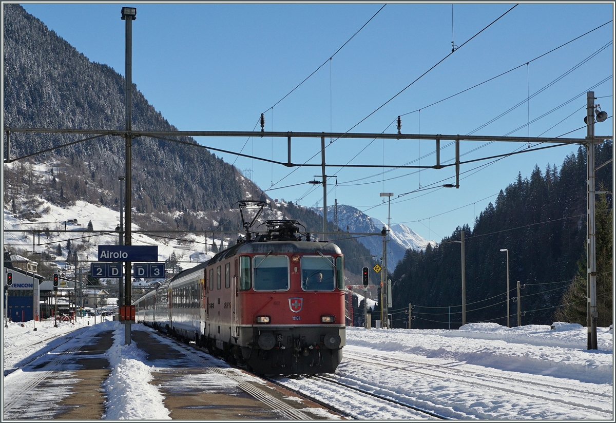 Bei kräftigem Gegenlicht erreicht die Re 4/4 II 11164 mit ihrem IR 2320 Locarno - Basel den Bahnhof Airolo. 
11. Feb. 2016
