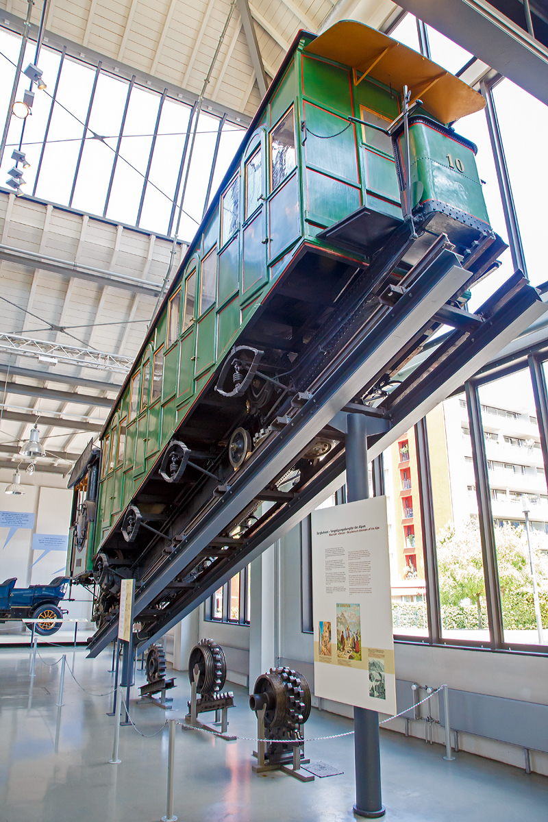 
Bhm 1/2 Zahnrad-Dampftriebwagen Nr.10 der Pilatus Bahn ausgestellt im Verkehrszentrum des Deutschen Museums in München (Theresienhöhe), hier am 16.06.2018. Leihgabe der Pilatus Bahnen.

Der Dampftriebwagen wurde 1900 von der SLM unter der Fabriknummer 1309 gebaut und an die Pilatus Bahn geliefert.

Mit Seilbahnen und Zahnradbahnen eroberten Touristen und Ausflügler am Ende des 19. Jahrhunderts die Einsamkeit der Berge. Als erster Schweizer Berg erhielt der sanfte Rigi 1875 die erste Bergbahn Europas. Nach dessen erfolgreicher Eroberung galt es dem schroffen und sagenumwobenen Pilatus am Vierwaldstätter See mit einer Bergbahn zu Leibe zu rücken. Eine besondere technische Herausforderung stellte dabei die starke Neigung der bevorzugten Trasse dar.

Eduard Locher entwickelte dafür 1888 ein Zahnstangensystem. Dank der liegenden Anordnung seiner Fischgrätenzahnstange und dem horizontalen Zahneingriff mit dem liegenden Zahnradpaar war eine Steigung von 48 % realisierbar.

Am 4. Juni 1889 dampfte der erste fahrplanmäßige Zug zum Pilatus. Er brauchte für die 4,3 Kilometer lange Strecke 70 bis 80 Minuten. Bereits 1895 reisten 40.000 Besucher per Zahnradbahn auf den Pilatus. Neun Dampftriebwagen waren dafür im Einsatz. Später kamen noch die Triebwagen 10 (1900) und 11 (1909) hinzu..

Die Triebwagen versahen größtenteils bis zur Umstellung auf elektrischen Betrieb im Jahre 1937 ihre Dienste. Mit den elektrischen Triebwagen konnte man mit weniger Personal in kürzerer Zeit mehr Gäste befördern. Bis auf die Dampftriebwagen 9 und 10 wurden die restlichen Fahrzeuge noch im selben Jahr verschrottet. Wagen 9 blieb bis 1981 als Reserve bei der Pilatusbahn und ist seitdem im Verkehrshaus der Schweiz in Luzern ausgestellt, Wagen 10 ist eine Dauerleihgabe des Verkehrshauses an das Deutsche Museum in München.

Heute fahren jährlich über 250.000 Besucher mit der steilsten Zahnradbahn der Welt auf den Pilatus, um von hier einen Blick auf die Schweizer Alpenwelt zu werfen.

TECHNISCHE DATEN:
Spurweite: 	800 mm
Achsformel:  2z
Länge über Puffer: 10.300 mm
Achsabstand der Laufräder: 7.200 mm
Leergewicht: 7,6 t 
Dienstgewicht:  13,2 t
Kohlevorrat: 500 kg
Wasservorrat: 880 l
Höchstgeschwindigkeit: 3,6 km/h (bergwärts) / 3 km/h (talwärts)
Leistung: 73 PS
Treibzahnraddurchmesser: 	409 mm
Zahnradsystem: 	Locher
Zylinderdurchmesser: 	235 mm
Kolbenhub: 300 mm
Kesselüberdruck: 12 bar
Anzahl der Heizrohre: 	130
Rostfläche: 	0,40 m²
Strahlungsheizfläche: 	2,40 m²
Verdampfungsheizfläche: 	21,0 m²
Steigung max.: 	48 %
Sitzplätze: 	35
