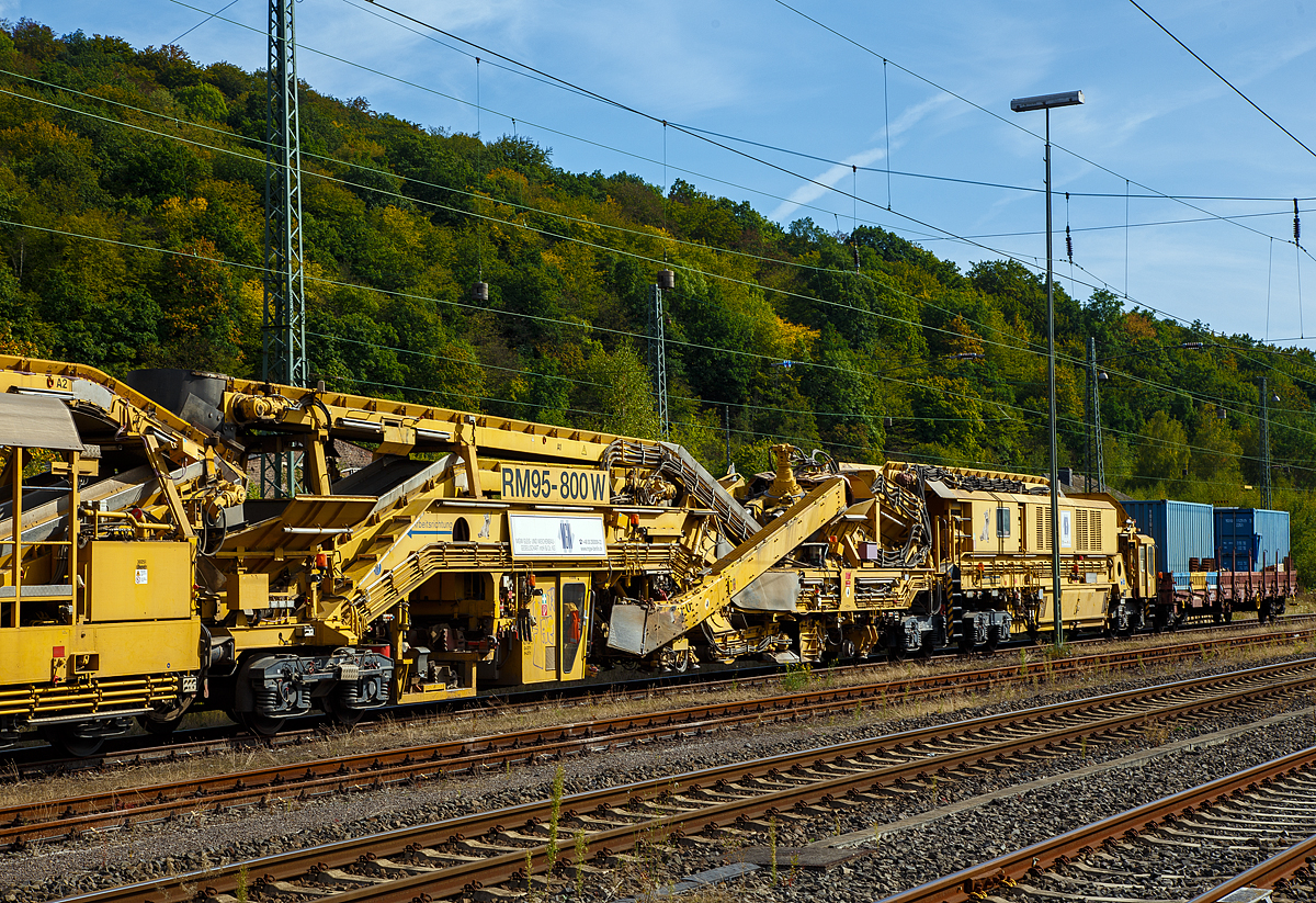 
Bild 2
Die Plasser & Theurer Bettungsreinigungsmaschine RM 95-800 W der MGW Gleis- und Weichenbau-Gesellschaft mbH & Co. KG (Berlin) ist am 20.09.2020 im Bahnhof Dillenburg abgestellt. Hier der Bereich der  Reinigungsmaschine AHM  und ATH. In der linken Einheit (AHM) befindet sich die Aushubkette und die Schotterrückführung (recycelt oder recycelter mit neuen Schotter vermischt).

Die Grundmaschine wurde 2010 von Plasser & Theurer unter den Fabriknummern 5221 bis 5224 gebaut, sie hat die VDM Nr. 99 80 9414 001-4 D-MWGB.
Rechts am Zugende noch der Schutzwagen 3999 010-6 der Gattung Res.