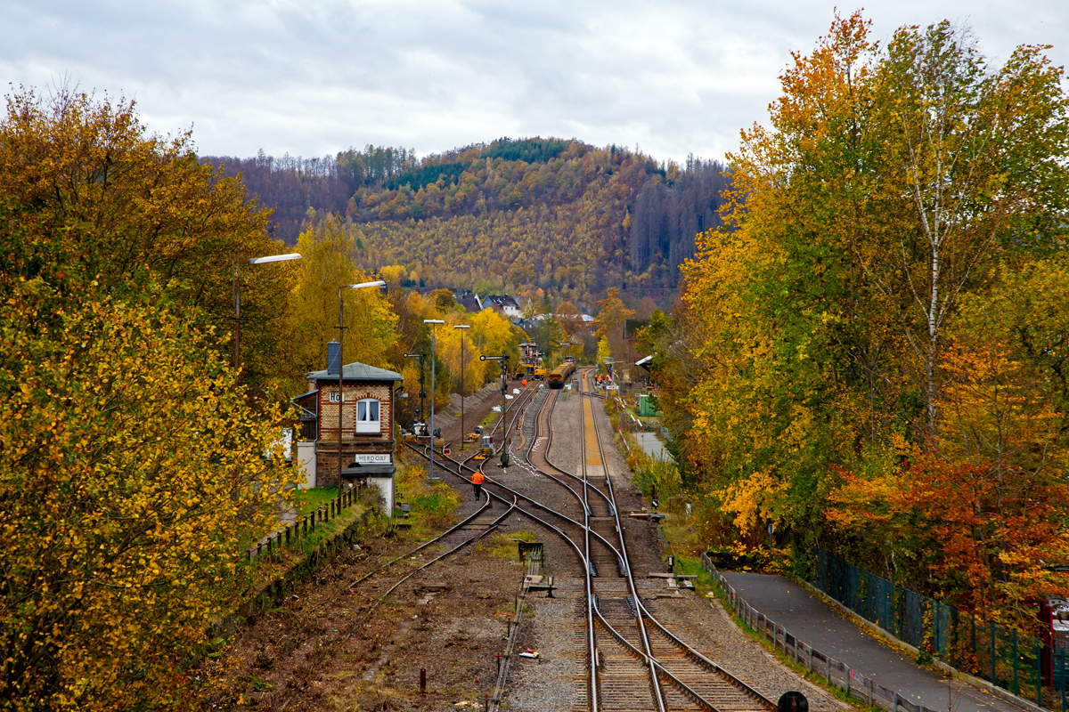 
Blick von der Brücke Wolfsweg („Achenbachs Brücke“) auf den Bahnhof Herdorf am 02.11.2020. Am Sonntag den 01.11.2020 war auf der Baustelle Ruhetag, der Oberbau von Gleis 4 wurde heute Morgen demontiert, nun hat der Aushub vom Schotterbett begonnen. Auf Gleis 2 steht die Vossloh G 12 „Karl August“ 92 80 4120 001-7 D-KAF der KAF Falkenhahn Bau AG mit einem zwei Seiten Kippwagenzug (Kippwagen MK 45 DH „LW-Kipper“, der Gattung Rlps), der mit dem Aushub (Altschotter) beladen wird. 

Der Altschotter wird später zum Recycling nach Bochum gefahren. 

