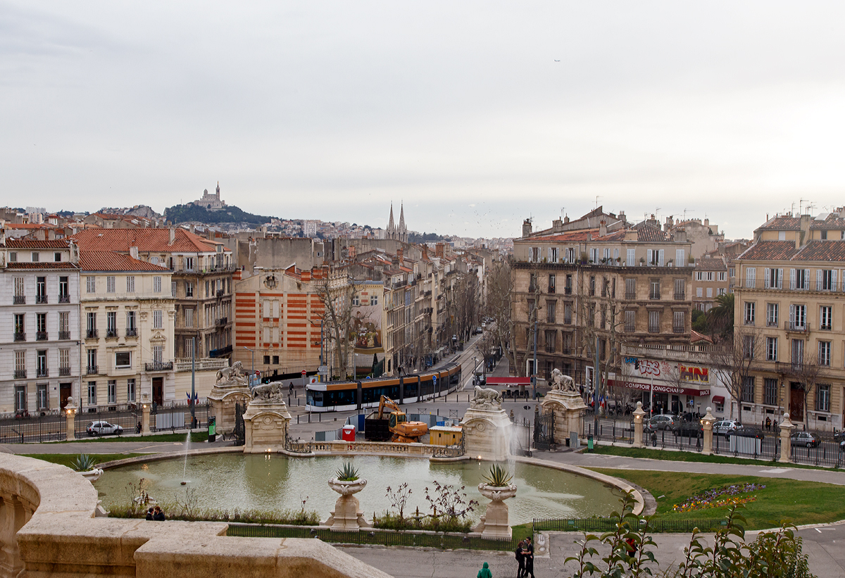 Blick vom Palais Longchamp in Marseille am 23.03.2015, unten f�hrt ein 7-teiliger Bombardier Flexity Outlook C - Cityrunner der Linie T 2 von der Station Longchamp (am Boulevard Longchamp) weiter in Richtung Blancarde Foch. Oben links im Bild, auf Marseille´s h�chster Erhebung (161 m) die Marien-Wallfahrtskirche Notre-Dame de la Garde.