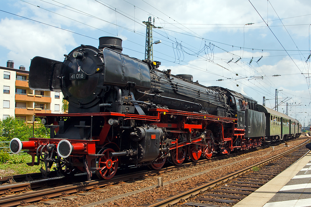 Dampfspektakel 2014 - Die schnelle Güterzug-Einheitsdampflokomotivene 41 018 der Dampflok-Gesellschaft München e.V., ex DB 042 018-2, ex DB 41 018, ex DR 41 018, fährt am 31.05.2014 mit einem planmäßigen Personenzug in den Hauptbahnhof Neustadt a d. Weinstraße ein. Diese Dampfzüge konnten mit einem normalen Nahverkehrsticket genutzt werden.


Zweizylinder-Güterzuglok wurde 1939 von Henschel & Sohn in Kassel unter der Fabriknummer 24320 gebaut. 

Im Januar 1961 rollte die Lok ins Ausbesserungswerk nach Braunschweig, wo sie einen neuen Kessel erhielt. Gleichzeitig wurde die 41 018 von Kohle auf Ölfeuerung umgebaut. Den Kesseltausch machten die zunehmenden Materialermüdung nötig, insgesamt wurden 107 Fahrzeuge der DB mit vollständig geschweißten Verbrennungskammerkesseln versehen, wie sie auch bei der Baureihe 03.10 eingebaut wurden. Neubaukessel produzierte bei Nennbelastung 13,32 t Dampf in der Stunde, der Ursprungskessel hingegen nur 11,58 t. Zudem wurden der vordere Bereich des Rahmens und der Umlauf geändert. Die Umstellung Ölhauptfeuerung erfolgte bei 40 Maschinen, diese wurden dann ab  01.01.1968 als 042 gebezeichnet. Die noch vorhandenen Loks mit Kohlefeuerung wurden ab 1968 als BR 041 bezeichnet, schieden aber bis 1971 aus dem Betriebsbestand aus.

Mit völlig neuem Aussehen kehrte die Maschine in den Betriebsdienst zurück, nun wieder beim Bw Osnabrück Hbf, um vor allem zwischen dem Ruhrgebiet und Hamburg schwere
Durchgangsgüterzüge zu bespannen. Das Bahnbetriebswerk Kirchwehye war eine weitere Station im Leben der 41 018, bevor sie im Mai 1967 nach Rheine in Westfalen kam, wo die
letzten 41er-Lokomotiven der damaligen Deutschen Bundesbahn zusammengezogen wurden. Um hier auch die schweren Güter- und Erzzüge auf der Emslandstrecke bis zu deren Elektrifizierung zu ziehen. Die BR 042 gehörte zu den letzten planmäßig eingesetzten Dampflokomotiven der DB. Die 41 186 bzw. nun DB 042 186-7 wurde am 28.09.1976 im BW Rheine ausgemustert, letzte Dampflokomotive der Baureihe 042 (DB 042 113-1) wurde ein Jahr später, am 26.10.1977, im Bahnbetriebswerk Rheine ausgemustert.


TECHNISCHE DATEN: 
Spurweite: 1.435 mm (Normalspur) 
Bauart:  1'D1'-h2
Gattung:  G 46.20
Länge über Puffer:  23.905 mm
Radstand mit Tender:  20.175 mm
Dienstgewicht:  101,5 t
Dienstgewicht mit Tender:  175,7 t
Radsatzfahrmasse:  20,2 t
Indizierte Leistung:  1.453 kW / 1.975 PS
Kessel: DB Neubaukessel 
Höchstgeschwindigkeit:  90 km/h vorwärts / 50 rückwärts 
Treibraddurchmesser:  1.600 mm
Laufraddurchmesser vorn:  1.000 mm
Laufraddurchmesser hinten:  1.250 mm
Steuerungsart:  Heusinger
Zylinderanzahl:  2
Zylinderdurchmesser:  520 mm
Kolbenhub:  720 mm
Kesselüberdruck:  16 bar
Tender:  2'2' T 34
Wasservorrat:  34 m³
Brennstoffvorrat:  12 m³ Öl
