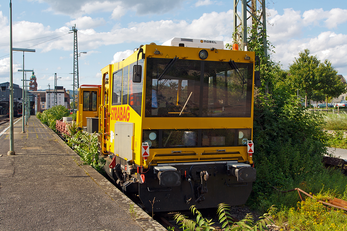 
Das Gleisarbeitsfahrzeug  99 80 9150 001-2 D-STRA der STRABAG Rail, ein Robel Bamowag 54.20, ist am 11.08.2014 beim Hauptbahnhof Wiesbaden angestellt. 

Der Bamowag 54.20 wurde 2010 von der ROBEL Bahnbaumaschinen GmbH in Freilassing unter der Fabriknummer 57.20-0003 gebaut. Das GAF hat in beiden Kabinen einen F�hrerstand, wobei Kabine mit dem TEREX Greifer sich auf einem Drehkranz befindet. 

Technische Daten (laut Anschriften): 
Spurweite: 1.435 mm 
L�nge �ber Puffer: 14.400 mm 
Achsabstand: 9.000 mm 
Kleinster bef. Gleisradius: R 95 m 
Zul. Streckenklasse: C2/CM2 und h�her 
Eigengewicht: 37.000 kg 
Nutzlast: 5 t Zul. 
Anh�ngelast: 100 t 
H�chstgeschwindigkeit: 100 km/h 
Zur Mitfahrt zugel. Personen: 5