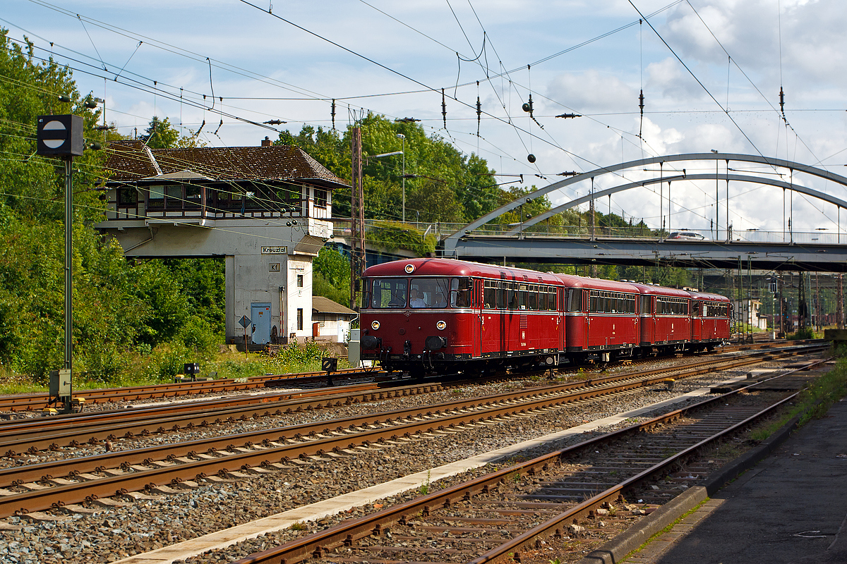 
Das Südwestfälisches Eisenbahnmuseum in Siegen hatte das bekannte Lokschuppenfest (16./17. Aug. 2014), anlässlich dieses fanden Schienenbus Pendelfahrten zwischen Siegen und Kreuztal statt. Hier passiert am 16.08.2014 die vierteilige Uerdinger-Schienenbus-Garnitur vom Förderverein Schienenbus e.V. aus Menden (Sauerland) das Fahrdienstleiter Stellwerk Kreuztal (Kf) und erreicht gleich den Bahnhof. 

Die Garnitur bestand aus (von vorne nach hinten): 

Motorwagen 9580 0796 690-5 D-EVG, ex DB 796 690-6, ex DB 798 690-4, ex DB VT 98 9690, ein echter  Uerdinger  (1960 bei der Waggonfabrik Uerdingen gebaut). Zuletzt wurde er vom Bw Siegen aus eingesetzt, wo er am 11. November 1995 ausgemustert wurde.

Beiwagen 9580 0996 299-3 D-EVG, ex DB 996 299-4, ex DB 998 299-2, ex DB VB 98 2299, von Rathgeber 1961 gebaut und bis 31.12.1981 im BW Betzdorf(Sieg) geheimatet. Ausgemustert wurde er  1996 im Bw Tübingen.


Beiwagen 9580 0996 309-0 D-EVG, ex DB 996 309-1, ex DB 998 309-9, ex DB VB 98 2309, von Rathgeber 1960 gebaut und am 30.06.1994 beim Bw Gießen ausgemustert.

Motorwagen 9580 0796 802-6 D-EVG, ex DB 796 802-7, ex DB 798 802-5, ex DB VT 98 9690, ein Lizenzbau 1961 von MAN. Zuletzt wurde er vom Bw Siegen aus eingesetzt, wo er am 30. November 1995 ausgemustert wurde.

Die beiden Motorwagen werden jeweils von zwei Diesel-Unterflurmotoren des Typs Büssing U 10 der Büssing AG, mit einer Leistung von  je 110 kW (150 PS) angetrieben. Die Leistungsübertagung erfolgt über ZF Sechs-Gang-Getriebe mechanisch auf die Achsen.

Die einzelnen Wagen haben im Laufe ihres Betriebslebens zahllose unterschiedliche Nebenbahnen befahren haben, von denen heute teilweise allenfalls noch ein Bahndamm auszumachen ist.
Aber alle waren mal hier in der Region beheimatet, was heute hier die LINT sind das waren früher die Uerdinger.
