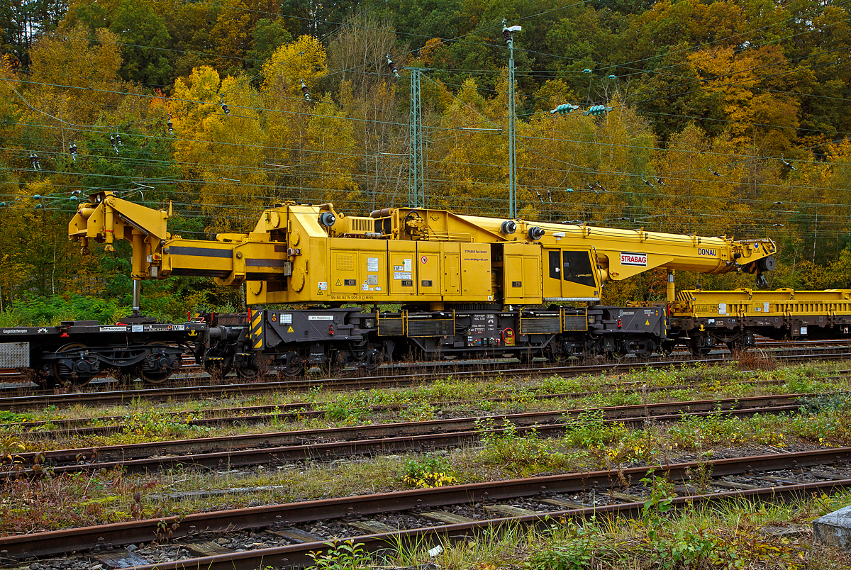 Der 150 t Kirow Gleisbaukran KRC 1200+ (ein Kirow MULTI TASKER KRC 1200+,  99 80 9419 005-0 D-BRS  „DONAU“  (ex 97 82 55 508 17-5) der STRABAG Rail GmbH ist am 27.10.2021 in Transportstellung in Betzdorf/Sieg abgestellt.  BRS steht für Strabag BMTI Rail Service GmbH (Berlin). 

Der Kran wurde 2009 von Kirow Ardelt AG in Leipzig unter der Fabriknummer 152500 gebaut. Er wird als Schweres Nebenfahrzeug Nr.: 99 80 9419 005-0 (ehemals 97 82 55 508 17-5) geführt und hat die EBA-Nr. EBA 09C02A001. 

Der Ausleger stützt sich auf dem Ausleger-Schutzwagen 99 80 9320 005-8 D-BRS ab und der Gegengewicht-Teleskoparm stützt sich auf dem Gegenlastwagen 99 80 9320 001-7 D-BRS ab.

Der Kran gehört zu einer der größten Gleisbaukranklassen, hat aber in der Transportstellung durch die Abstützungen auf den Kranauslegerschutzwagen und den Gegenlastwagen geringere Streckenlast (Meterlast) von max. 7,4 t/m, als seine kleineren Brüder.
Das Gegengewicht ist ausfahrbar und separat bis ± 30º  schwenkbar, sodass ein Einschwenken in den Bereich des Nachbargleises vermieden und ein profilfreies Arbeiten ermöglicht wird.

TECHNISCHE DATEN von dem Kran:
Spurweite: 1.435 mm
Eigengewicht  (in Transportstellung) : 111,0 t 
Länge über Puffer:  15.000 mm  (+13.000 mm Gegenlastwagen,+ 20.000 mm Ausleger-Schutzwagen)
Motorleistung:  254 kW bei 2.200 U/min
max. Geschwindigkeit im Zugverband: 100 km/h
max. Geschwindigkeit im Eigenantrieb: 19 km/h
Achsanzahl:  8 (in 4 Drehgestelle bzw. 2 Doppeldrehgestelle)
Drehzapfenabstand: 10.000 mm
Drehzapfenabstand im Drehgestell 1 und 2: 2.300 mm
Achsabstand in den Einzeldrehgestellen: 1.100mm
Ergebene Achsabstände in m: 1,1 / 1,2 / 1,1/ 6,6 / 1,1 / 1,2 / 1,1
Achsfolge: 1'A'1A'A1'A1'
Radsatzlast Transport Kran: max. 13,8 t
Radsatzlast Gegengewichtswagen:  max. 20,0 t
Meterlast (Streckenlast) in Transportstellung Kran max.: 7,4 t/m
Höhe in Transportstellung:  4.300 mm
Breite in Transportstellung:  3.100 mm
max. Ausladung vor Puffer:  21.000 mm
max. Traglast bei max. Ausladung:  40 t