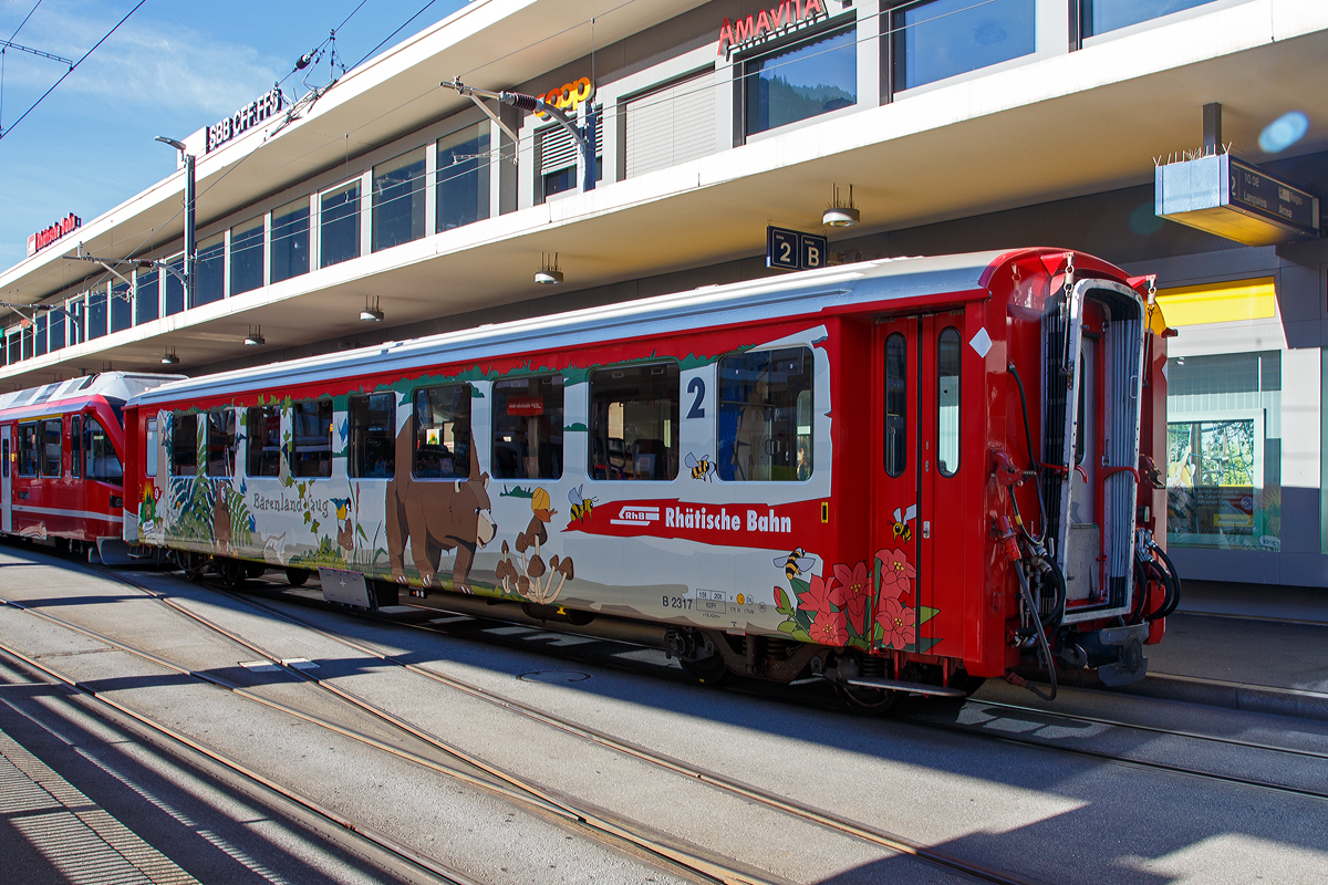 Der 4-achsige RhB Einheitswagen I (EW I) - B 2317  B�renland Arosa , ein 2. Klasse Personenwagen am 01.11.2019 in Chur (Bahnhofsvorplatz).

Im August 2018 wurde bei Arosa das B�renland er�ffnet. F�r diesen Anlass hat die RhB die Einheitswagen EW I B 2315 -2319 zu B�renlandwagen innen und au�en umgestaltet. Mit der Bahn anreisende Besucher k�nnen sich bereits w�hrend der Bahnfahrt zum Beispiel mit B�chern einstimmen. 

Mit mehr als 100 Fahrzeugen bilden die als Einheitswagen I bezeichneten Personenwagen bis heute die gr��te Serie im Rollmaterialbestand der RhB. Das Fahrzeugkonzept wurde Anfang der sechziger Jahre in enger Zusammenarbeit zwischen Industrie und RhB entwickelt. Als Neuheit galten damals die Einstiegsbereiche mit WC und Stauraum f�r sperriges Gep�ck an den Wagen�berg�ngen. Folglich weicht das Konzept deutlich von den Mitteleinstiegswagen aus den vierziger Jahren ab.

Die ersten von FFA und SIG gebauten Einheitswagen I wurden Ende 1963 in Betrieb genommen. In einem Zeitraum von etwa zehn Jahren wuchs der Bestand an EW I kontinuierlich. Neben den 18,42 m langen Wagen, die haupts�chlich auf dem Stammnetz eingesetzt werden, kamen auch Sonderbauformen mit Aluminiumwagenkasten hinzu. Zu diesen z�hlen die auf 14,19 m verk�rzten Fahrzeuge f�r den Einsatz auf der Berninabahn.

TECHNISCHE DATEN (B 2315-2319):
Hersteller Wagenkasten: FFA
Hersteller Drehgestelle:  SWP
Inbetriebsetzung: 1969
Betriebsnummern: B 2315-2319
Anzahl Fahrzeuge: 5
Spurweite: 1.000 mm
L�nge �ber Kupplung: 18.420 mm
Breite: 2.650 mm
Achsabstand im Drehgestell: 1.800 mm
Drehzapfenabstand: 12.830 mm
Gewicht: 13.000 kg
Sitzpl�tze: 62
zul. H�chstgeschwindigkeit: 90 km/h
Lauff�hig: Chur-Arosa, StN (Stammnetz) / MGB (Matterhorn Gotthard Bahn) 
Auf der BB (Berniabahn) w�re es m�glich, aber nur bis Alp Gr�m. Denn dahinter werden die Gleisradien zu eng. F�r die BB wurden verk�rzte Einheitswagen beschafft.