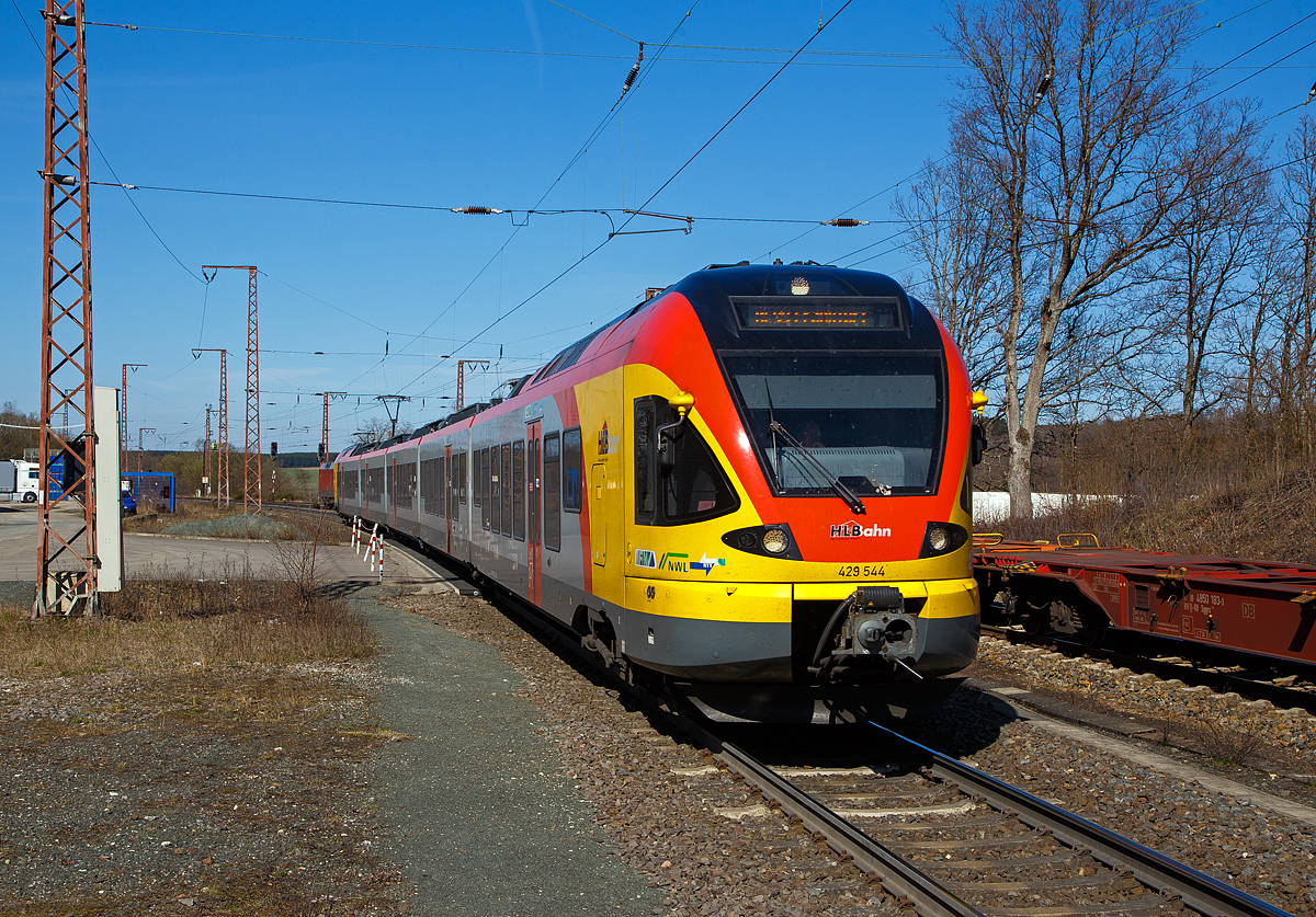 Der 5-teilige Stadler Flirt 429 544 / 429 044 der HLB (Hessischen Landesbahn) fährt am 30.03.2021, als RE 99  Main-Sieg-Express  (Siegen – Gießen – Frankfurt am Main Hbf), durch Rudersdorf (Kr. Siegen) über die Dillstrecke (KBS 445) in Richtung Gießen.

Hinten am Gleis hat die 152 124-4 der DB Cargo AG mit einem Containerzug noch Hp 0 und muss den Gegenverkehr abwarten. Ein Gleis war wohl unterbrochen.
