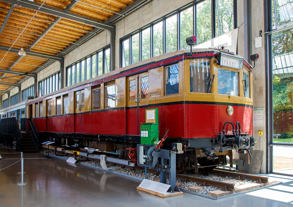 
Der ehemalige Berliner S-Bahn Triebwagen 275 625-2 (einer von vier Prototypen der Bauart Stadtbahn), ausgestellt im Verkehrszentrum des Deutschen Museums in München (Theresienhöhe), hier am 16.06.2018. Seit 2006 Leihgabe vom Verein Historische S-Bahn e.V., Berlin.

Der Triebwagen wurde 1927 von der WUMAG (Waggonbau Görlitz) gebaut.

Der Wagen hat die folgenden Fahrzeugnummern getragen:
1927 bis 1930 DRG elT 2187
1930 bis 1941 DRG (ab 1937 DR) elT 3110
1941  bis 1970 DR ET 165 040
1970 bis 1991 DR 275 625-2
1992 bis 1993 DR 475 161-6, war jedoch nie angeschrieben, da dieses bereits vorher abgestellt war. Umzeichnung erfolgte nur buchmäßig.

Als am 8. August 1924 der elektrische Betrieb auf der Vortortstrecke Bernau und im Folgejahr nach Oranienburg begann, suchte die Deutsche Reichsbahn-Gesellschaft (DRG) nach einem geeigneten Fahrzeugtyp für die geplante „Große Elektrisierung der Stadt-, Ring- und Vorortbahnen . Die Versuchszüge und die Bauart Bernau erwiesen sich schnell als wenig geeignet. Erst die Bauart Oranienburg brachte den Durchbruch: gleichlange Trieb- und Beiwagen, alle Achsen des Triebwagens waren angetrieben. Aus den vierzehn Herstellerfirmen wählte die DRG sechs aus, welche als Lieferkartell die Großserie fertigen sollte, die eine Weiterentwicklung der Bauart Oranienburg darstellte: leichtere Wagenkästen, bessere elektrische Ausrüstung. Der Probezug traf 1927 in Berlin ein, im selben Jahr begann die Serienfertigung. Bis 1931 wurden insgesamt 1276 Wagen geliefert. Bis heute ein Rekord! Die Wagen kamen von den Firmen in das neu errichtete Reichsbahnausbesserungswerk Berlin-Schöneweide und wurden dort von den Elektrofirmen AEG und Siemens (als Lieferantenkartell unter dem Namen Wasseg zusammengeschlossen) sowie Bergmann Electricitäts-Werke (BEW) und Maffei-Schwarzkopf-Werke (MSW), ebenfalls eine Liefergemeinschaft, ausgerüstet.

Mit den neuen Fahrzeugen begann am 6. Juni 1928 der elektrische Betrieb auf der Strecke Potsdam—Erkner, der ersten im Rahmen der Großen Elektrisierung. In den folgenden Jahrzehnten bildeten diese Fahrzeuge das Rückgrat der Berliner S-Bahn und wurden mehrfach modernisiert. So fuhren die Stadtbahner in Form der Baureihe 476/876 noch bis ins Jahr 2000 durch Berlin und das Umland. Diese Einsatzzeit von über 70 Jahren ist absolut untypisch für ein Schienenfahrzeug und war auch der besonderen politischen Situation in und um Berlin geschuldet.

Der Viertelzug 275 625/626 trug bei Auslieferung die Wagennummern 2187 (Triebwagen) und 5205 (Beiwagen) und gehörte damit zu einen von vier im Jahr 1927 gebauten Prototypen. Bei Auslieferung trugen der Viertelzug eine ungewöhnliche Farbgebung, da die dritte Wagenklasse komplett gelb und die zweite rot lackiert war. Während die anderen drei Prototypen verschrottet bzw. in U-Bahn-Wagen umgebaut wurde, blieb 275 625/626 erhalten und ging in die Sammlung des Vereins über.

TECHNISCHE DATEN:
Bauart : Stadtbahn
Baujahr: 1927 (Prototyp)
Spurweite:  1435 mm (Normalspur)
Achsformel: Bo'Bo'
Länge über Kupplung : 35.460 mm
Drehzapfenabstand: 11.800 mm
Drehgestellachsstand:  2.500 mm
Antriebsleistung:  360 kW (4 x GBM 700)
Höchstgeschwindigkeit: 80 km/h
Gewicht: 38 t
Zustand: 70er und 80er Jahre
Stromsystem: 750 V Gleichspannung