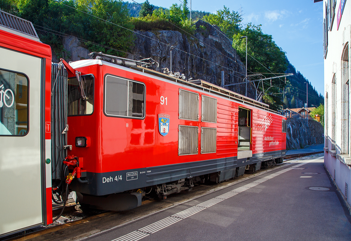 
Der Elektrische Zahnradgepäcktriebwagen MGB Deh 4 /4 II – 91 „Göschenen“, ex FO Deh 4/4 II – 91, steht am 01.08.2019 mit ihrem Schöllenenbahn Regionalzug nach Andermatt, im Bahnhof Göschenen zur Abfahrt bereit.

Der Gepäcktriebwagen wurde 1979 von SLM (mechanischer Teil, Lokomotivkasten) und BBC (elektrische Ausrüstung) gebaut.

Der Deh 4/4 II ist ein schmalspuriger Gepäcktriebwagen der Matterhorn-Gotthard-Bahn (MGB) für Adhäsions- und Zahnradbetrieb.

Weil die Furka-Oberalp-Bahn (FO) mit den Deh 4/4 I gute Erfahrungen gemacht hatte, beschaffte sie die Deh 4/4 II als Nachfolger. Im Zuge des Zusammenschlusses der FO mit der BVZ kamen sie zur neuen Gesellschaft Matterhorn-Gotthard-Bahn, wo sie nur noch als Deh 4/4 bezeichnet und, wenn nötig, anhand der Seriennummern 2.., 5.. und 9.. unterschieden werden.

Technische Daten:
Spurweite: 1.000 mm
Achsformel: Bo’Bo’
Länge über Puffer: 15.500 mm
Drehzapfenabstand: 8.800 mm
Achsabstand im Drehgestell: 2.790 mm
Größte Breite: 2.683 mm
Größte Höhe (bei abgesenkten Stromabnehmer): 3.880 mm
Leergewicht: 49,5 t (davon Mechanischer Teil 28 ,5 t)
Dienstgewicht: 51,0 t
Maximale Zuladung: 1,5 t
Gepäckraum Fläche: 10 m²
Höchstgeschwindigkeit: Adhäsion 60 km/h / Zahnstange 30 km/h
Stundenleistung: 1.032 kW
Dauerleistung: 936 kW
Stundenzugkraft am Rad: 117,2 kN
Dauerzugkraft am Rad: 101,2 kN
Maximale Zugkraft am Rad: 247,2 kN
Stromsystem: 11 kV 16,7 Hz AC
Anzahl der Fahrmotoren: 4
