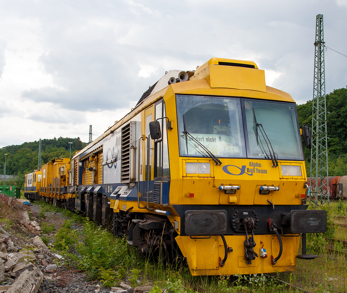 Der LINSINGER Schienenfr�szug SF 03 FFS, Schweres Nebenfahrzeug Nr. 99 80 9427 019-1 D-ALPHA (ex 97 33 07 502 18-5), der Alpha Rail Team GmbH & Co. KG, Berlin, ist am 11.06.2010, mit dem Materialwagen 31 80 D-ALPHA 399 8 079-6 Res und dem ex Motorturmwagen BRX 535, Schweres Nebenfahrzeug Nr. 99 80 9486 002-5 D-ALPHA (ex 97 99 02 501 18-2) in Betzdorf (Sieg) abgestellt. Der ehemalige (umgebaute) Motorturmwagen BRX 535 wird als Steuerwagen verwendet, zudem dient er als Aufenthalts-, Werkstatt- und Ger�tewagen.

Und so funktioniert’s:
Die Fr�smaschine mit integrierter Messtechnik zur L�ngs- und Quer�Profil�Messung verf�gen �ber zwei hintereinander platzierte Fr�seinheiten sowie eine Schleifeinheit, die �ber das Bedienpult der F�hrerkabine pr�zise zu steuern sind. 
Nach dem Prinzip „fr�sen, fr�sen, feinschleifen“ bewegt sich der Zug mit einer maximalen Geschwindigkeit von 25 m/min �ber die zu sanierenden Streckenabschnitte. Der entstehende Spanabfall wird in einem Bunker zwischengelagert. Der Schleifstaub wird in einen separaten Beh�lter abgesaugt.

Dabei ist eine Autonomie bis zu 16 Stunden. Daf�r ist auch auf dem Beiwagen ein zus�tzlicher Sp�ne-Container installiert. Es kann also problemlos beispielsweise ein Wochenende durch�ge�arbeitet werden, ohne dass ein Ausbunkern der Sp�ne notwendig wird.

Es ist m�glich, den gesamten Schienenkopf in nur einer �berfahrt fertig zu bearbeiten. Die Schiene wird mittels Fr�sen reprofiliert (Umfangsfr�sen) und im selben Arbeitsgang geschliffen (Umfangsschleifen). Das bedeutet, dass die Querprofilabweichungen, Riffeln und L�ngswellen sowie Besch�digungen der Schienenoberfl�che in nur einem Arbeitsdurchgang beseitigt werden.
Dieser Arbeitszyklus erfolgt mit einem Fr�swerkzeug, welches mit mehrfach verwendbaren HM-Platten best�ckt ist. Mit diesem Werkzeug wird ein genaues Querprofil erzeugt.

Hinter den beiden Fr�sstationen ist auf jeder Seite eine Schleifstation positioniert. Diese wird lediglich zur Verbesserung der optischen Oberfl�chenqualit�t verwendet. Die Schleifscheiben sind mit dem erforderlichen Schienenquerprofil profiliert und arbeiten ebenfalls in Umfangsrichtung. 

Leistungsmerkmale
– Maximale Geschwindigkeit: bis zu 25 m/min

Fr�sen des Schienenprofils
– Minimaler Kurvenradius: 150 m
– Bearbeitungstiefe der Fahrfl�che: 0,3 bis 1,8 mm
– Spurberichtigung: max. Abtrag pro Schiene bis zu 2,5 mm

Das Ergebnis: Wiederherstellung des Schienenprofils mit einer
– Querprofilgenauigkeit: +/- 0,2 mm
– L�ngsprofilgenauigkeit: 0,02 mm
– Qualit�t der Oberfl�chenrauigkeit Ra < 10 �m