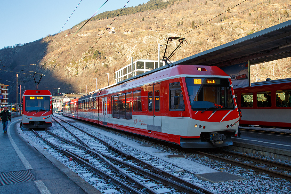 
Der MGB ABDeh 4/10 „KOMET“ ein Stadler Niederflur-Panoramatriebzug mit Zahnrad- und Adh�sionsantrieb steht am 30.12.2015 als Regionalzug im Bahnhof  Brig (Bahnhofsvorplatz) zur Abfahrt nach Fiesch bereit. W�hrend links zwei gekuppelte (dreiteilige) MGB ABDeh 4/8 „KOMET“ als Regionalzug zur Abfahrt nach Zermatt bereit stehen. 

Diese Triebz�ge, wie auch der BDSeh 4/8 sind von Stadler gebaute elektrische Schmalspur-Niederflur-Panoramatriebz�ge, das K�rzel „KOMET“ steht f�r „KOmfortabler MEterspur-Triebzug“. 

Der ABDeh 4/10 ist ein vierteiliger Triebzug mit 1. und 2. Klasseabteil, der ABDeh 4/8 ist ein dreiteiliger Triebzug mit 1. und 2. Klasseabteil und der BDSeh 4/8 ist ein dreiteiliger Triebzug dieser hat kein 1. Klasseabteil, besitzt aber einen gro�en Gep�ckbereich f�r bis zu 36 Kofferkulis, diese k�nnen �ber Klapptritte eben in die beiden Endwagen geschoben werden. Die BDSeh 4/8 sind meist im Pendelverkehr zwischen dem autofreien Zermatt und dem Autoparkplatz in T�sch im Einsatz, w�hrend die ABDeh 4/10 und ABDeh 4/8 auf dem ganzen Stammnetz der MGBahn unterwegs sind. Der vierteilige ist jedoch nicht f�r gr��ere Steigungen (Maximalsteigung 179 Promille) aufweisende Sch�llenenbahn Andermatt–G�schenen zugelassen, der dreiteilige Varianten haben diese Zulassung.

Jeder Triebzug besteht aus einem hochflurigen, einstiegslosen, vierachsigen Triebwagen, auf den auf einer Seite ein und auf der anderen Seite ein bzw. zwei (beim ABDeh 4/10) antriebslose Elemente mit Niederflureinstiegen aufgesattelt sind. Der Triebwagen verf�gt �ber zwei zweiachsige Drehgestelle mit je einem Fahrmotor pro Achse. Der Antrieb erfolgt im reinen Adh�sionsbetrieb �ber die acht R�der der Triebdrehgestelle und im Zahnradbetrieb zus�tzlich �ber vier Zahnr�der f�r die bei der MGB verwendete Zahnstangen Systems Abt. Die aufgesattelten Elemente besitzen jeweils nur ein Lauf-/Bremsdrehgestell am �u�eren Wagenende und st�tzen sich am anderen Ende auf den n�chsten Wagen auf. Alle Drehgestelle sind luftgefedert. Die hochflurigen Bereiche des Triebzuges verf�gen �ber Panoramafenster. 

Dank einer automatischen Mittelpufferkupplung vom Typ FK (Schwab FK-9-6) k�nnen die Triebz�ge in Mehrfachtraktion der unterschiedlichen KOMETen und den passenden Steuerwagen (Niederflur-Gelenksteuerwagen ABt 2131–34 und Gep�ck-Steuerwagen BDkt 2231–33) fahren, was eine Anpassung an die Kapazit�tsbed�rfnisse erm�glicht.


TECHNISCHE DATEN des ABDeh 4/10:
Anzahl Fahrzeuge: 4 St�ck (Nummer 2011-2014)
Spurweite:  1.000 mm
Achsanordnung: 2‘Bo‘Bo‘2‘2
L�nge �ber Kupplung: 74.728 mm
Fahrzeugbreite:  2.650 mm
Fahrzeugh�he: 3.950 mm
Dienstgewicht, tara: 95,0 t
Achsabstand Triebdrehgestell: 2.540 mm
Lauf-/Bremsdrehgestell: 1.800 mm
Triebraddurchmesser (neu): 796 mm
Laufraddurchmesser (neu): 685 mm
Fu�bodenh�he Niederflurbereiche: 415 mm
Fu�bodenh�he Hochflurbereiche: 950 mm bzw. 1100 mm
Einstiegbreite: 1.600 mm
Sitzpl�tze: 1. Klasse 47 / 2. Klasse 141 
Dauerleistung am Rad: 1.000 kW
Max Leistung am Rad: 1.300 kW
Anfahrzugskraft: 200 kN
H�chstgeschwindigkeit:  80 km/h (Adh�sion) / 40 km/h (Zahnrad)
Zahnradsystem: 	Abt (2 Lamellen)
Anzahl Antriebszahnr�der: 4
Speisespannung: 11 kV, 16.7 Hz

Abweichende  DATEN des ABDeh 4/8:
Anzahl Fahrzeuge: 8 St�ck (Nummer 2021-2028)
Achsanordnung: 2‘Bo‘Bo‘2‘
L�nge �ber Kupplung: 56.664 mm
Dienstgewicht, tara: 77,0 t
Sitzpl�tze: 1. Klasse 30 / 2. Klasse 114

Abweichende  DATEN des BDSeh 4/8:
Anzahl Fahrzeuge: 4 St�ck (Nummer 2051-2054)
Achsanordnung: 2‘Bo‘Bo‘2‘
L�nge �ber Kupplung: 52.014 mm
Dienstgewicht, tara: 71,8 t
Sitzpl�tze: 120 (2. Klasse)
Pl�tze f�r Gep�ckrolli: 36
Anfahrzugskraft: 180 kN

Quellen: Stadler Rail und Wikipedia
