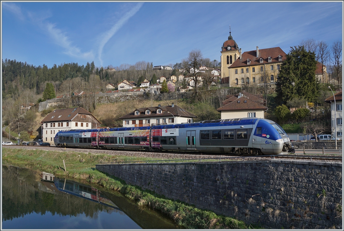 Der SNCF X 76679/680 verlässt als TER 18108 von La Chaux de Fonds nach Besançon den Ort Morteau. Im Hintergund ist die Kirche Notre-Dame de l'Assomption zu sehen.  

16. April 2022