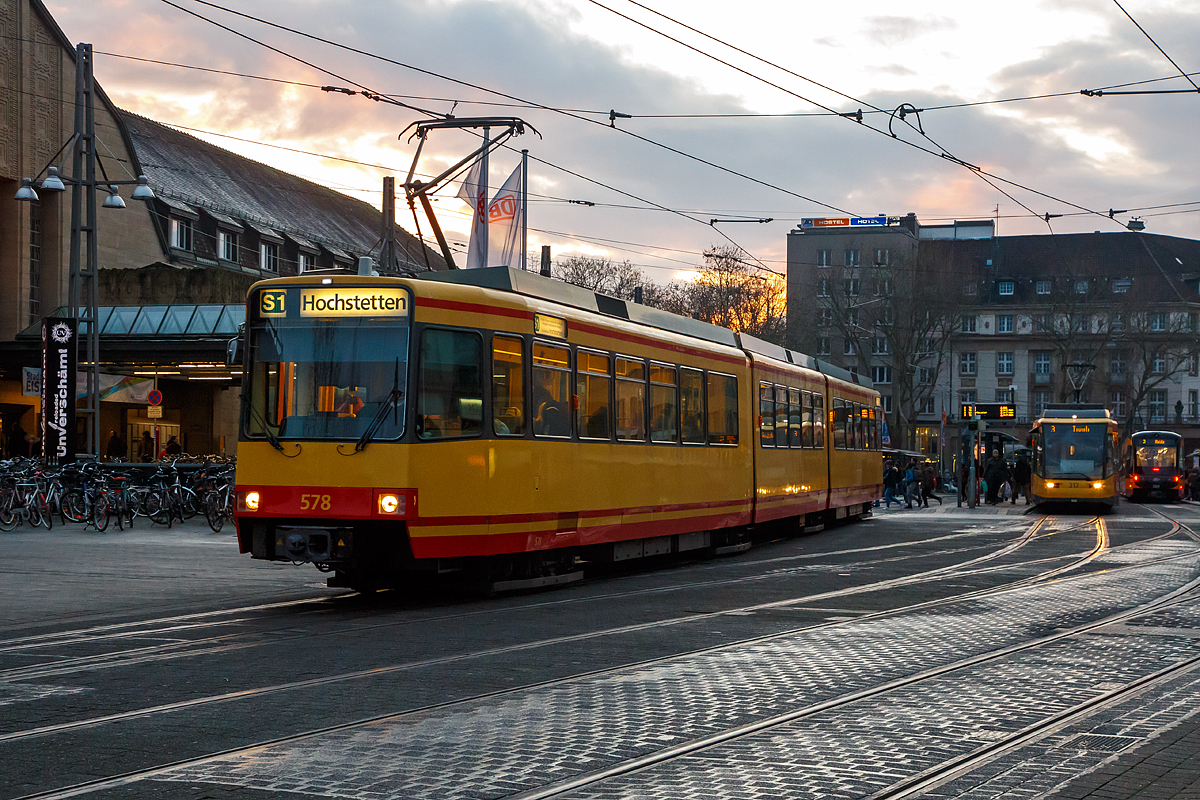 
Der Stadtbahntriebwagen AVG 578, ex AVG 538, ein DUEWAG GT8-80C, verl�sst am 16.12.2017, als S 1von Bad Herrenalb nach Hochstetten, die Station Karlsruhe Hbf (Vorplatz).

Der GT8-80C ist ein Stadtbahnfahrzeug, auf der Basis des Fahrzeugtyps GT6-80C durch Einf�gen eines zus�tzlichen Mittelteils, bei der DUEWAG f�r  die Verkehrsbetriebe Karlsruhe und die Albtal-Verkehrs-Gesellschaft hergestellt wurde (15 St�ck), die elektrische Ausr�stung wurde von BBC beziehungsweise ABB zugeliefert. Weitere 25 St�ck (wie dieser) entstanden durch den Umbau aus GT6-80C. 

Das Konstruktionsprinzip ist wie beim GT6-80C ebenfalls von dem von DUEWAG gebauten Hochflur-Stadtbahn-Fahrzeug Stadtbahnwagen Typ B abgeleitet und entspricht dem des GT6-80C. Der GT8-80C unterscheidet sich dadurch, dass er ein weiteres Mittelteil und ein weiteres Jakobs-Drehgestell besitzt. Er ist dadurch mit 38,41 Metern zehn Meter l�nger. Die Kapazit�t steigerte sich im Auslieferungszustand um 24 Sitz- und 33 Stehpl�tze auf 119 Sitzpl�tze und 124 Stehpl�tze. Die zwei Lieferserien unterscheiden sich durch ihre unterschiedlichen Mittelteile. Die 1989 gelieferte dritte Lieferserie erhielt ein Mittelteil mit Dachrandverglasung (Panoramaabteil), Klimaanlage und Teppichboden, jedoch keine zus�tzliche T�r. Die vierte Lieferserie (1991) erhielt zugunsten eines schnelleren Fahrgastwechsels ein Mittelteil mit einer T�r. Die Dachrandverglasung und die Klimaanlage entfielen bei dieser Lieferserie. Dies war auch so bei den 20 Umbauten 1993 und 1997, wobei die ersten 5 Umbauten 1990 das Panoramaabteil erhielten.

Im Gegensatz zu den Stadtbahnwagen Typ B ist das Fahrzeug als Einrichtungswagen ausgelegt und besitzt nur auf einer Seite T�ren. Ebenfalls ist nur ein voll eingerichteter F�hrerstand vorhanden, w�hrend im Heck nur ein Hilfsf�hrerstand zur Verf�gung steht. 

TECHNISCHE DATEN:
Anzahl: 15 + 25 aus GT6-80C umgebaute
Hersteller: 	DUEWAG, BBC 
Baujahre: 	1989, 1991
Achsformel: 	B'2'2'B'
Spurweite: 	1435 mm (Normalspur)
L�nge �ber Kupplung:  38.410 mm
L�nge:  37.370 mm
H�he:  3.405 mm
Breite:  2.650 mm
Drehzapfenabstand:  10.000 mm / 9.770 mm / 10.000 mm
Achsabstand im Drehgestell:  2.100 mm
Leergewicht:  51,0 t 
H�chstgeschwindigkeit: 	80 km/h
Dauerleistung: 	2 � 280 kW
Antrieb: Gleichstrommotor (2x)
Stromsystem: 	750 Volt Gleichspannung
Bremse: 	Motorbremse, Federspeicherbremse, Schienenbremse
Steuerung: Choppersteuerung
Kupplungstyp: 	Scharfenberg
Sitzpl�tze: 	119
Stehpl�tze: 124
Fu�bodenh�he: 	1.000 mm
