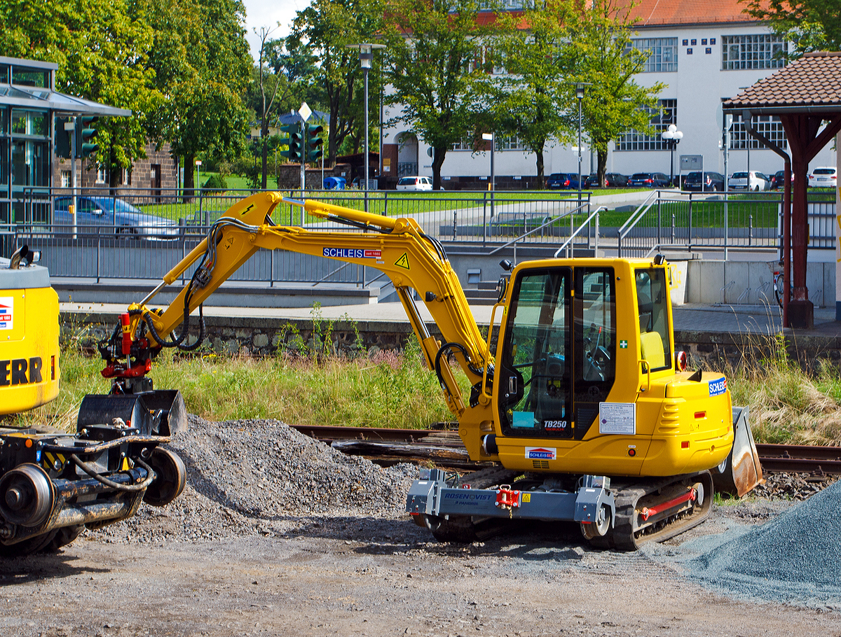 
Der Takeuchi TB 250 ZW Zweiwege-Minibagger (Kompaktbagger) der Firma SCHLEIS GmbH - Bauunternehmung, selbstfahrendes schienengebundenes Ger�t Registrier-Nr. G 9915 009, steht am 20.08.2014 beim Bahnhof Bad Nauheim. 

Der vom japanischen Hersteller Takeuchi gebaute Kompaktbagger TB 250 ZW hat eine Breite von 1,85 m und H�he von 2,51 m. So ist es ihm m�glich, auch in U-Bahn-Tunneln zu fahren und dort, ohne die Tunnelumgebung, Bahnsteige, Geb�ude oder technischen Einrichtungen zu ber�hren, seine Arbeit zu leisten. Und das mit flottem Tempo, denn das hydraulisch angetriebene Schienenfahrwerk beschleunigt den TB 250 ZW auf 20 km/h.  Angetrieben von einem 28,4 kW/38 PS Motor, �bernimmt der 5,8 t schwere Zweiwegebagger Takeuchi TB 250 ZW Arbeiten, die sonst von gr��eren Baggern ausgef�hrt werden.  

Das Schienenfahrwerk ist von dem schwedischen Hersteller Rosenqvist / Pandrol, vom Typ HY-RAIL MINI<5 TONS. An der einen Seite werden die Laufr�der von � 350 mm einzeln durch je einen Hydraulikdrehmotor angetrieben, die mitlaufende Laufachse besitzt einen Raddurchmesser von 250 mm.

TECHNISCHE DATEN: 
Einsatzgewicht:  5.900 kg
Motorleistung:  28,4 / 38,0 kW
H�chstgeschwindigkeit: 20 km/h
Grabtiefe:  3.625 mm
�berladeh�he:  4.085 mm
Ausr�stung:  DB-Zulassung, Hub,- und Schwenkbegrenzung, DB-Sicherheitspaket, Schienenfahrwerk