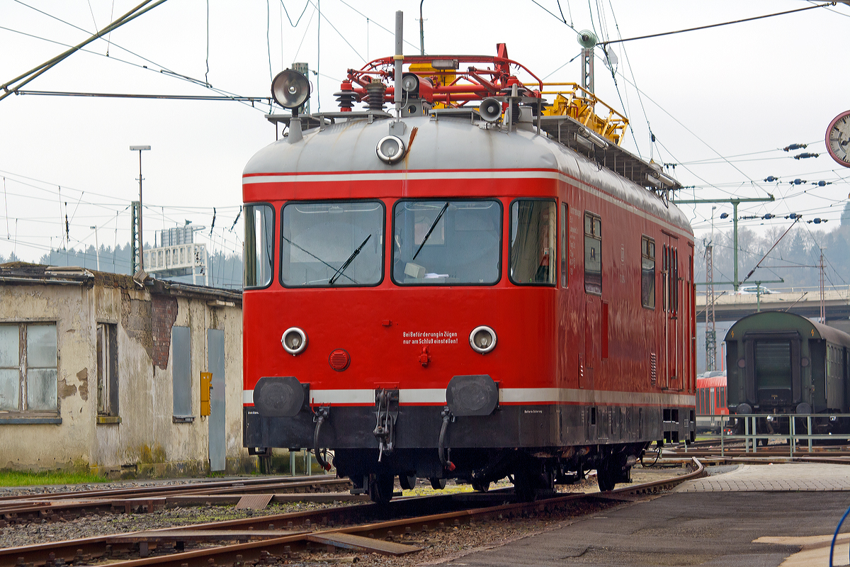 
Der Turmtriebwagen 701 099-4, ex DB 701 099-4, ex Deutsche Bundesbahn -  Kassel 6206, der Lokvermietung Aggerbahn (Andreas Voll e.K., Wiehl) ist am 22.11.2014 beim Südwestfälische Eisenbahnmuseum in Siegen abgestellt. Die Aufnahme entstand vom Gehweg aus, durchs Tor.

Der Turmtriebwagen wurde 1964 bei WMD in Donauwörth unter der Fabriknummer 1512 gebaut.  Bei der DB war er in Kassel, Marburg und Gießen beheimatet. Nach der Ausmusterung kam er zur VEB - Vulkan-Eifel-Bahn in Gerolstein, bis er zur Aggerbahn kam. Die altrote Farbgebung hier entspricht der  ursprünglichen  Farbgebung. 

Die Turmtriebwagen (TVT), der Baureihe 701, auf Basis der Uerdinger VT 98 wurden von 1955 bis 1974 in 13 Bauserien von der DB beschafft. 

Die Regelturmtriebwagen werden zum Bau und zur planmäßigen Untersuchung der elektrischen Fahrleitungen sowie zur Beseitigung von Störungen und Schäden eingesetzt, aber auch für Brücken- und Bauwerkprüfungen.
Der Rohbauwagenkasten besteht aus einer Schweißkonstruktion in Profilbauweise aus Stahl. Für die Sonderausrüstung, die geforderte hohe Zuladung und die heb- und senkbare Arbeitsbühne wurde der Wagenkasten mit einem besonderen Untergestell verstärkt. 

Der Wagengrundriss ist in zwei Führerstände und einen 26 m² großen Werkstattraum aufgeteilt. Die Führerstände sind durch Drehtüren mit dem Werkstattraum verbunden. Die Werkstatt dient insbesondere zum Lagern von Ersatzteilen, Werkzeugen und Arbeitsvorrichtungen, die in Regalen an den Seitenwänden untergebracht sind. Eine Werkbank ermöglicht kleinere Reparaturarbeiten. Außerdem sind ein Schreibtisch, ein Kleiderschrank und ein beheizbarer Kleidertrockenschrank vorhanden. 

Zur Beobachtung der Fahrleitungsanlage während der Fahrt befindet sich im Werkstattraum eine Beobachtungskanzel mit Podest. Zwei Suchscheinwerfer ermöglichen eine Kontrolle der Fahrleitung auch bei Dunkelheit. Auf dem Dach des Regelturmtriebwagens ist ein Stromabnehmer zur Prüfung der Fahrdrahtlage und des Zusammenwirkens von Fahrleitung und Stromabnehmer aufgebaut. Mit einer Verstelleinrichtung kann der Anpressdruck reguliert werden.

Die Arbeitsbühne ist hydraulisch heb und senkbar sowie elektrisch - im Notfall auch manuell - drehbar. Um auch in den Querfeldern der Bahnhöfe jeden Punkt erreichen zu können, ist zusätzlich eine auf 8 m Steighöhe ausziehbare Stahlleiter auf der Arbeitsbühne vorhanden. Mit einer aufsteckbaren Zusatzleiter lassen sich Fahrleitungsbauteile noch in 15 m Höhe über Schienenoberkante erreichen. Die Hub- und Senkbewegungen sowie das Schwenken der Bühne ist von der Arbeitsbühne aus steuerbar. 

Führerstände, Beobachtungskanzel und Arbeitsbühne sind durch eine Lautsprecheranlage verbunden. An das Unterhaltungspersonal außerhalb des Wagens können Anweisungen über schwenkbare Lautsprecher gegeben werden. Für Sprechverbindungen mit Bahnhöfen ist eine Funksprechanlage eingebaut. 

Die Maschinenanlage besteht aus zwei voneinander unabhängigen 6-ZylinderUnterflur-4-Takt-Dieselmotoren, vom Typ Büssing U10, mit Kraftstoff- und Kühlanlage, einer hydraulischen Kupplung, einem Sechs-Ganggetriebe mit elektromagnetischer Schaltung und einem Achswendegetriebe. Die für das Verlegen eines neuen Fahrdrahtes notwendige geringe Dauergeschwindigkeit von 5 km/h wird mit einer kombinierten Drehzahl-Füllungsregelung ermöglicht.

Die Druckluft für Bremse und Nebenverbraucher wird von zwei Luftpressern erzeugt, die von den Fahrmotoren mit angetrieben werden. Als Stromquellen dienen, bei ruhendem Dieselmotor, vier Einzelbatterien, die über 4 x 700 W-Lichtmaschinen aufgeladen werden. Zusätzlich sind die Batterien über eine Ladeeinrichtung aus einem 220 V Ortsnetz aufladbar. Auf der Arbeitsbühne und in der Werkstatt stehen Steckdosen zur Verfügung. 

Die Heizung des Wagens erfolgt über die Motorenwärme. Zwei Ölheizgeräte ermöglichen ein Vorheizen und Warmhalten der Maschinenanlage und heizen den Werkstattraum sowie die Führerstände, wenn der Motor nicht in Betrieb ist und bei extrem tiefen Außentemperaturen.

Technische Daten:
Achsformel: AA
Spurweite:  1.435 mm (Normalspur)
Länge über Puffer:  13.950 mm
Länge des Wagenkastens:  12.750 mm 
Breite des Wagenkastens:   3.000 mm  
Wagenhöhe von SO bis Oberkante Dach: 3.700 mm
Achsstand: 6.000 mm  
Raddurchmesser: 900 mm  
Dienstgewicht: 24,6 t (bei voller Zuladung 29,0 t)
Kleinster befahrbarer Gleisbogen:  125 m  
Motor:  6-Zylinder Unterflur 4-Takt-Dieselmotor, Typ Büssing U10
Motorleistung:  2 x 110 kW (150 PS) bei 1.900 U/min 
Höchstgeschwindigkeit:   90 km/h 
Mindestgeschwindigkeit beim Prüfen: 5 km/h  
Kupplungstyp:  Schraubenkupplung


Daten der Arbeitsbühne:  
Länge der Plattform: 4.550 mm
Breite der Plattform: 1.660 mm
Hubhöhe: 1.000 mm
Hubzeit: 16 sec.
Fußbodenoberkante der Bühne über SO: 4.150 bis 5.150 mm
Schwenkbereich nach beiden Seiten: 90° (elektrischem Antrieb)/100°(Handbetrieb)
Seitliche Verschiebbarkeit der Leiter aus der Mittellage:  je 380 mm
Länge der ausgezogenen Leiter: 8.000 mm (ohne Aufsteckleiter)/10.000 (mit Aufsteckleiter)
Zulässige senkrechte Belastung der Bühne :  300 kg
Gesamtgewicht der zu hebenden Teile:  1.600 kg
Tragkraft der hydraulischen Hubvorrichtung:   3.000 kg
