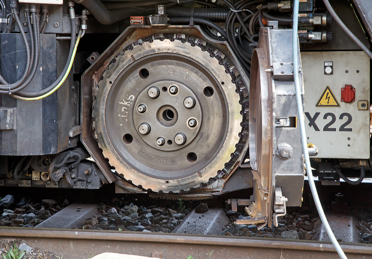 
Detailbild 1 - Der LINSINGER Schienenfräszug SF 03 FFS, Schweres Nebenfahrzeug Nr. D-DB 97 33 07 003 18-4, der DB Netz AG (SFM 601), steht am 04.05.2015 in Kreuztal. 

Die Abdeckung ist offen, so kann man hier einen der drei Fräser (Messerköpfe) auf der linken Seite sehen. Der Messerkopf hat einen Durchmesser von 600 mm und ist mit ca. 220 Wendescheidplatten bestückt. Dies bedeutet schon einen größeren zeitlichen Aufwand, wenn man die Wendescheidplatten drehen oder auswechseln muss. 

Gut zusehen auch wie er befestigt wird, zentriert über vier Passbolzen, sowie auf vier Gewindebolzen auf die dann Muttern aufgeschraubt werden.

Der Messerkopf ist von LINSINGER, Typ MK-Ø600-10x22/60E2M04/1:40 Nr.5737
