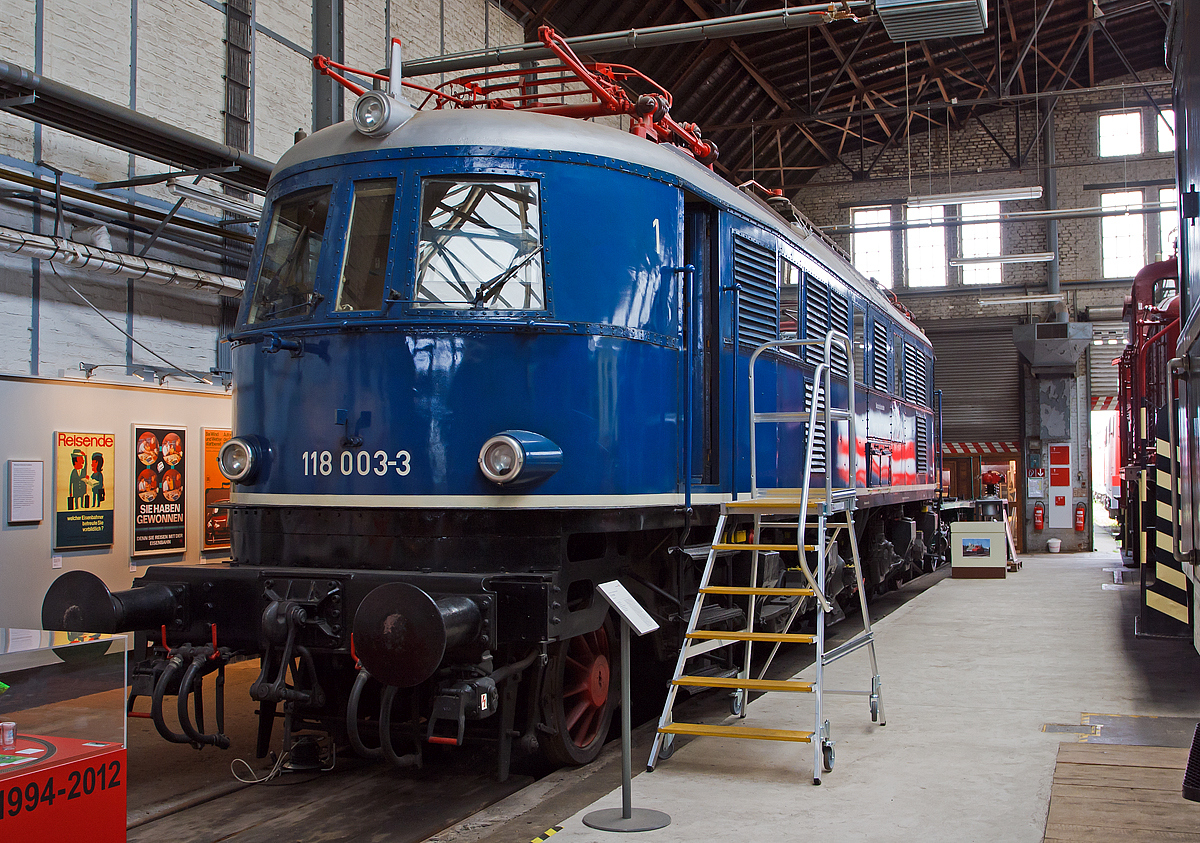 Die 118 003-3, ex DR E 18 003, ausgestellt am 18.07.2012  in der Fahrzeughalle des DB-Museums Koblenz-Lützel.

Die Schnellzug-Elektrolokomotive 118 003-3 wurde 1935 von der Allgemeine Elektricitäts-Gesellschaft (AEG) unter der Fabriknummer 4876 gebaut und als E 18 003 an die Deutsche Reichsbahn geliefert, wie die meisten E 18 blieb sie nach dem Krieg im Westen und wurde so zur DB E18 003. Mit der Einführung der EDV-Nummer wurde sie zum 01.01.1968 umgezeichnet in DB 118 003-3. Am 31.07.1984 wurde sie bei der Deutschen Bundesbahn ausgemustert.

Die Lokomotiven der Baureihe E 18 waren bestimmt zur Beförderung schwerer Schnellzüge mit hohen Geschwindigkeiten. Die Lokomotiven wurden für die neu elektrifizierten Strecken München-Stuttgart und München-Nürnberg-Leipzig-Berlin entwickelt.

Viele Baugruppen, wie zum Beispiel die Motoren oder der AEG Federtopfantrieb, wurden von der E 04 übernommen. Der Lokkasten hingegen war eine Neuentwicklung, der den Grundsätzen der Aerodynamik und der Stromlinie Rechnung trug. Die E 18 hatte keinen genieteten, sondern einen geschweißten Fahrzeugrahmen. Die Laufachsen waren für die Laufruhe mit der jeweils ersten – verschiebbaren – Treibachse in einem AEG-Kleinow-Gestell zusammengefasst. Der Antrieb erfolgte über Federtöpfe. Die ursprünglichen der Stirnfront angepassten Leuchten wurden bei der DB bis auf wenige Ausnahmen durch Einheitsleuchten ersetzt. 

Bedingt durch den Zweiten Weltkrieg wurde die weitere Beschaffung der E 18 zugunsten der wichtigeren Kriegsloks E 44 und E 94 eingestellt. Bis Kriegsende wurden daher nur 53 Lokomotiven gebaut.
Nach dem Krieg verblieben bei der Deutschen Bundesbahn 41 Lokomotiven, die weiterhin im Schnellzugdienst eingesetzt wurden. Mitte der sechziger Jahre wurden die leistungsfähigen Lokomotiven durch die neu in Auslieferung befindlichen E 10 verdrängt. Die Loks wurden nun vermehrt im Nahverkehr eingesetzt, was der Schnellzuglok nicht sonderlich bekam. Die Schäden an Schaltwerk und Bremse häuften sich. In den siebziger Jahren erhielten einige E 18 die Vorrüstung für die automatische Kupplung. Es wurden sogenannte Verschleißpufferbohlen angebracht, die das elegante Aussehen der Loks nachteilig beeinflussten. Die E 18 03 ist eine derart umgebaute Lokomotive. Die Loks der BR E 18 wurden bis 1984 planmäßig eingesetzt.

Im normalen Schnellzugdienst konnten die Maschinen 935-t-Schnellzüge in der Ebene mit 140 km/h, 990-t-Züge bei 5 Promille mit 100 km/h, 600-t-Züge bei 10 Promille mit 100 km/h und 360-t-Züge bei 20 Promille mit 75 km/h befördern.

TECHNISCHE DATEHN:
Spurweite:  1435 mm (Normalspur) 
Achsformel:  1'Do1'
Länge über Puffer:  16.920 mm
Dienstgewicht:  108,5 t
Radsatzfahrmasse:  18,1 t
Höchstgeschwindigkeit:  150 km/h
Stundenleistung:  3.040 kW
Dauerleistung:  2.840 kW
Anfahrzugkraft:  206 kN
Treibraddurchmesser:  1.600 mm
Stromsystem:  15 kV 16 2/3 Hz AC
Anzahl der Fahrmotoren:  4
Antrieb:  Kleinow-Federtopfantrieb
Kupplungsart: Schraubenkupplung